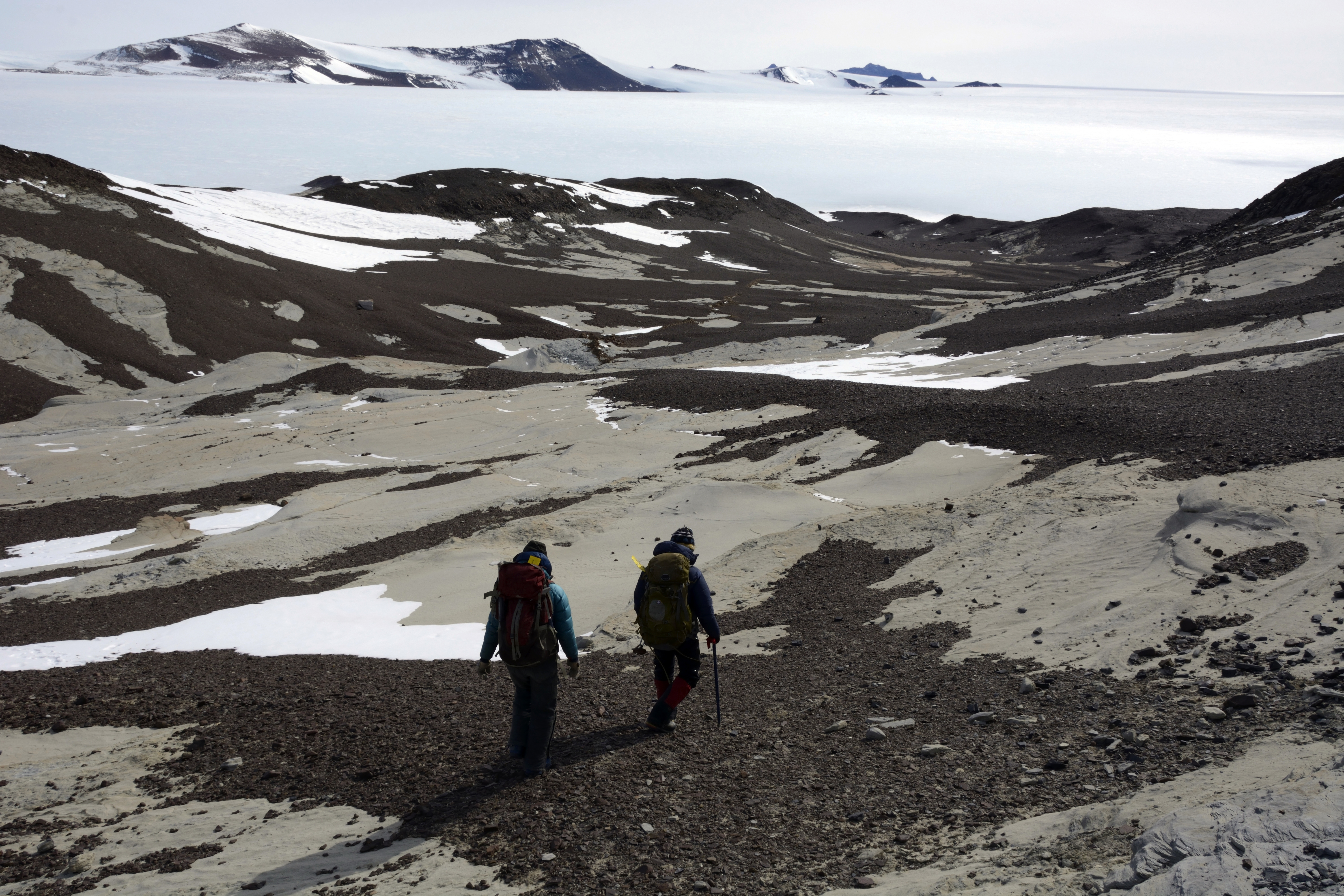 People hike through barren valley.