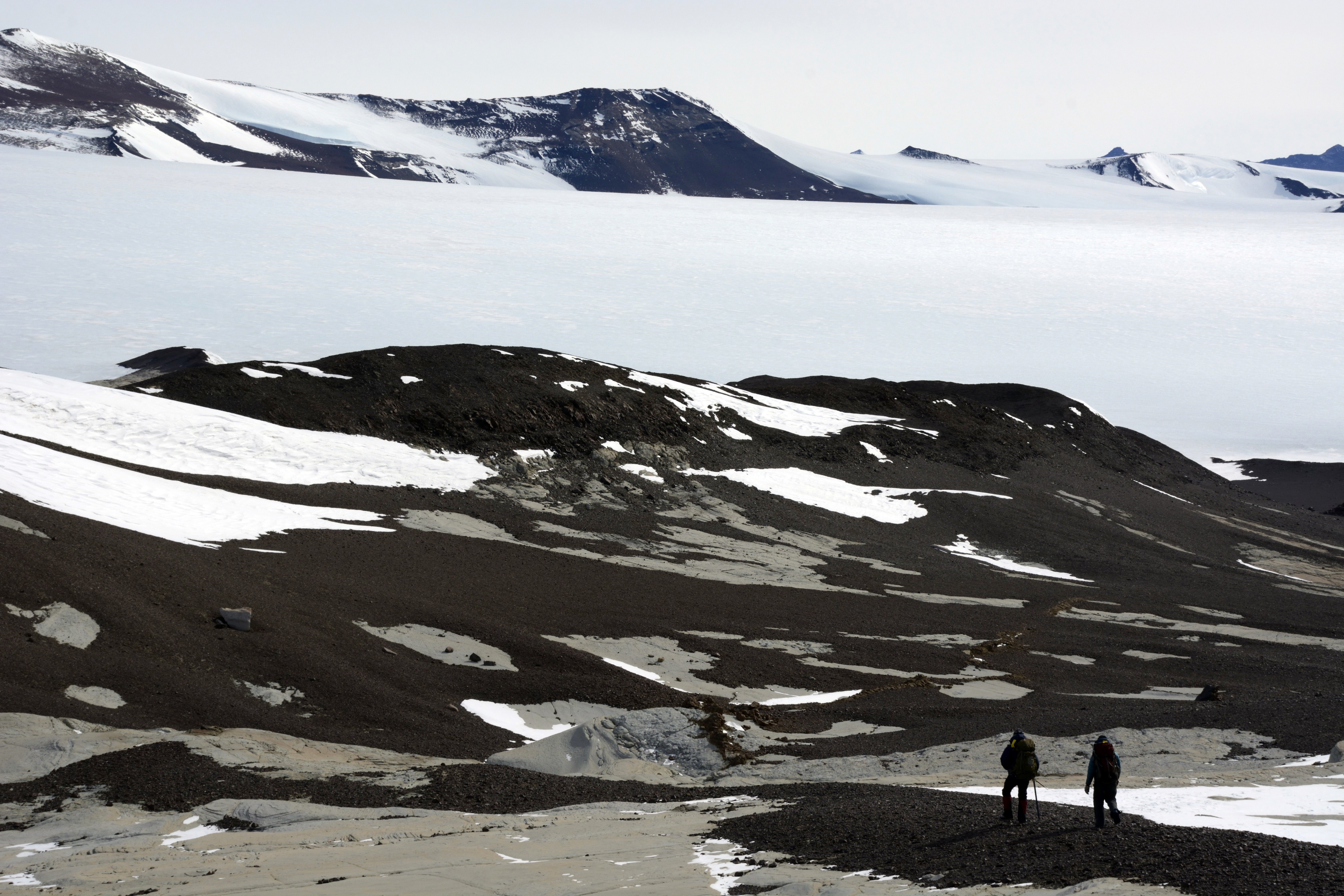 People hike through barren valley.