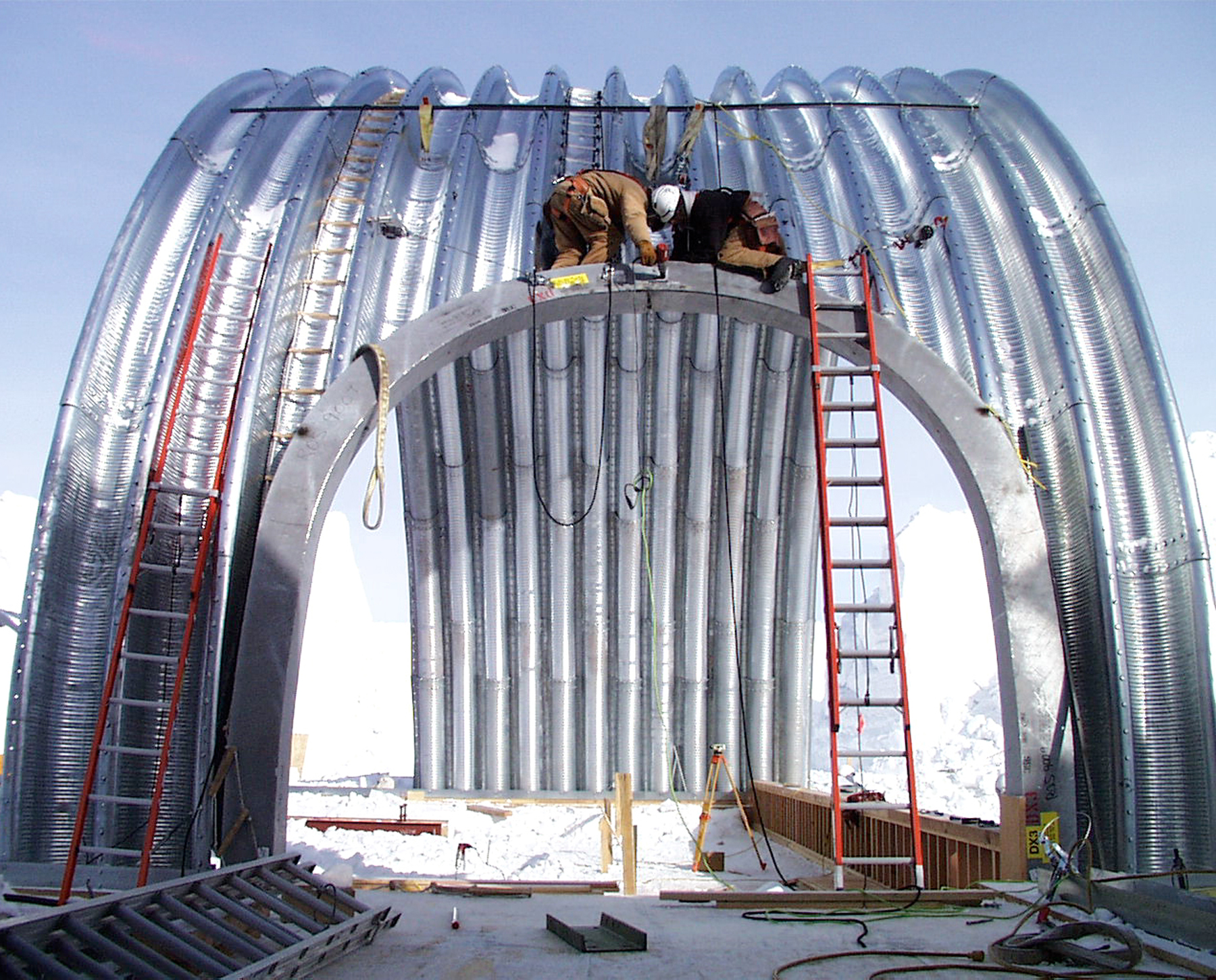 Construction workers work on a corrugated arch.