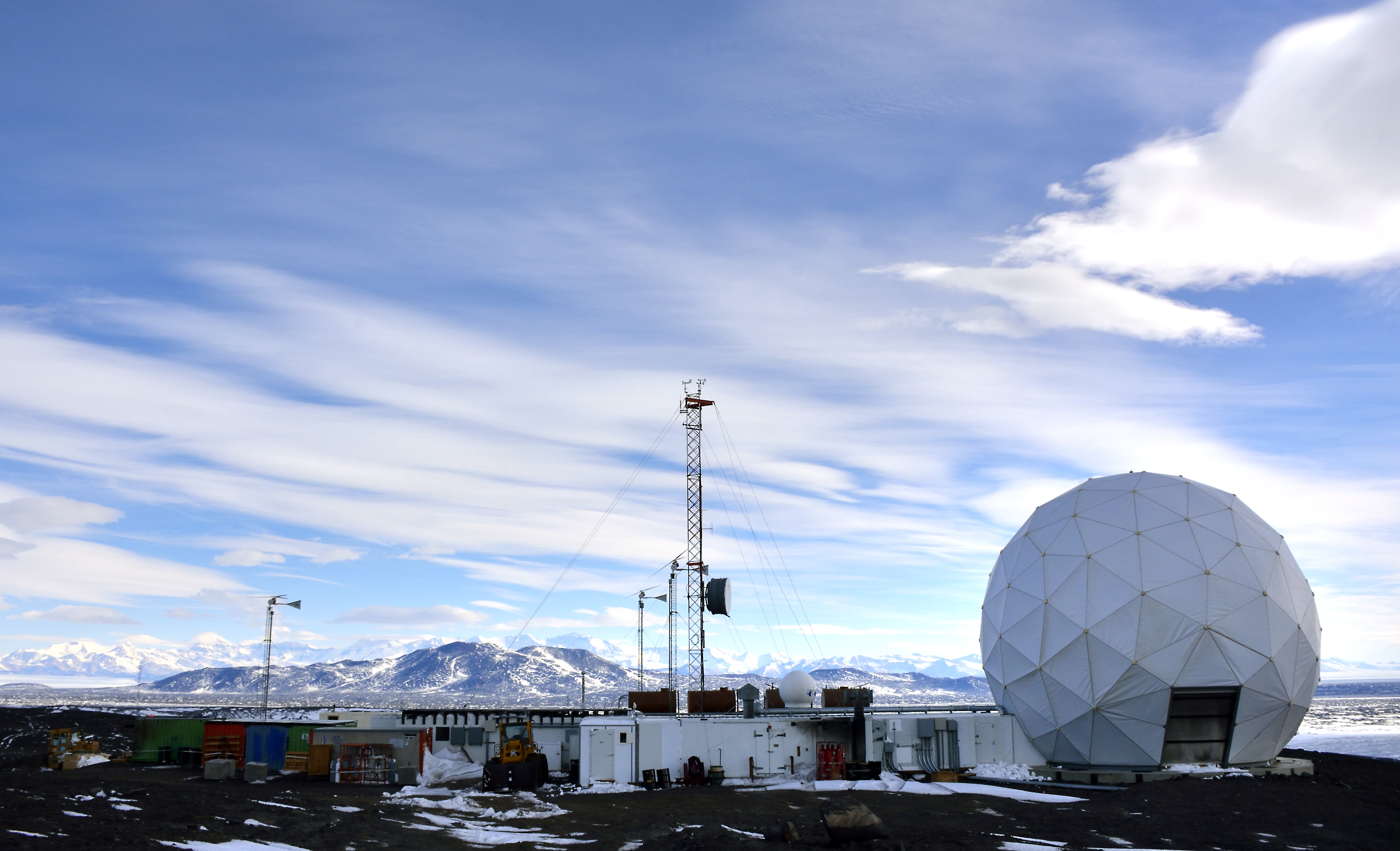 A large ball sits in front of several small buildings. 