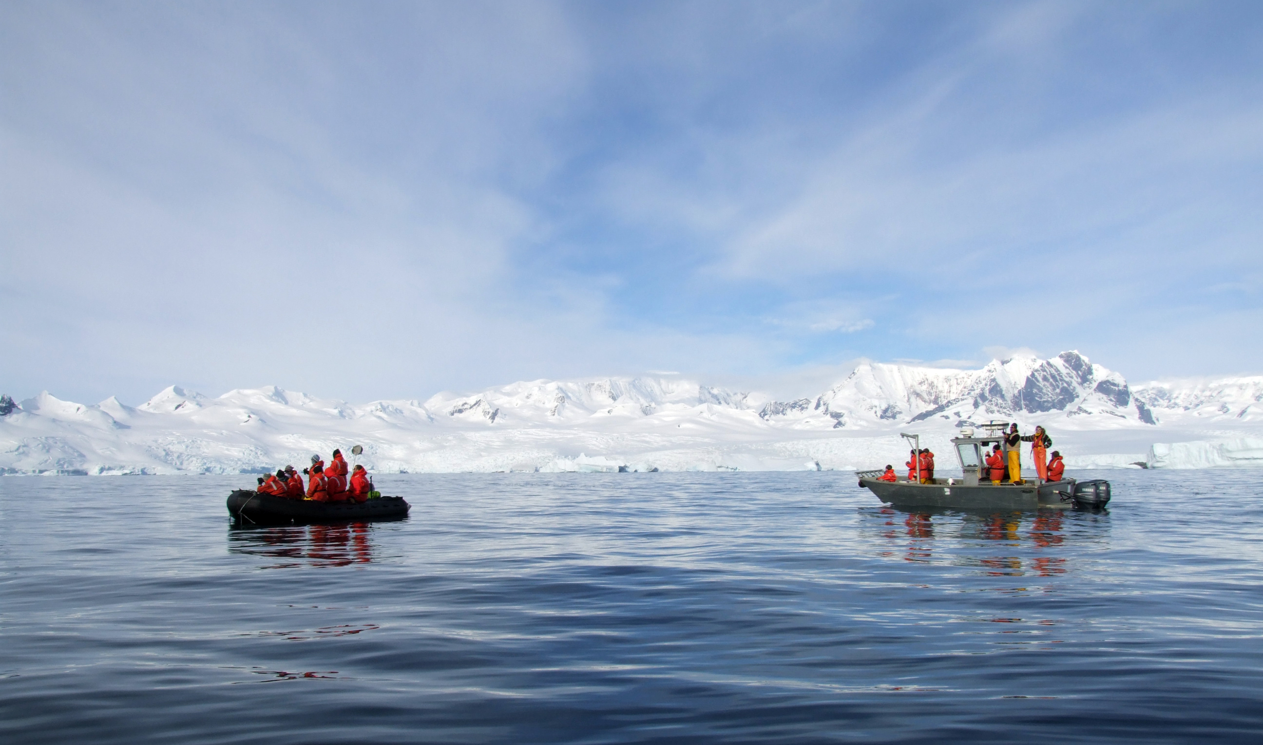 People in boats ride near icy place.