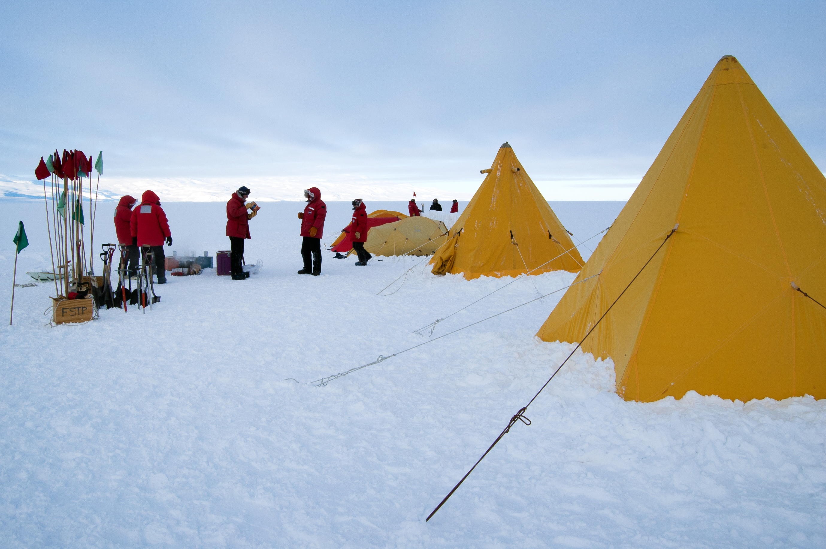 People set up tents on snow.