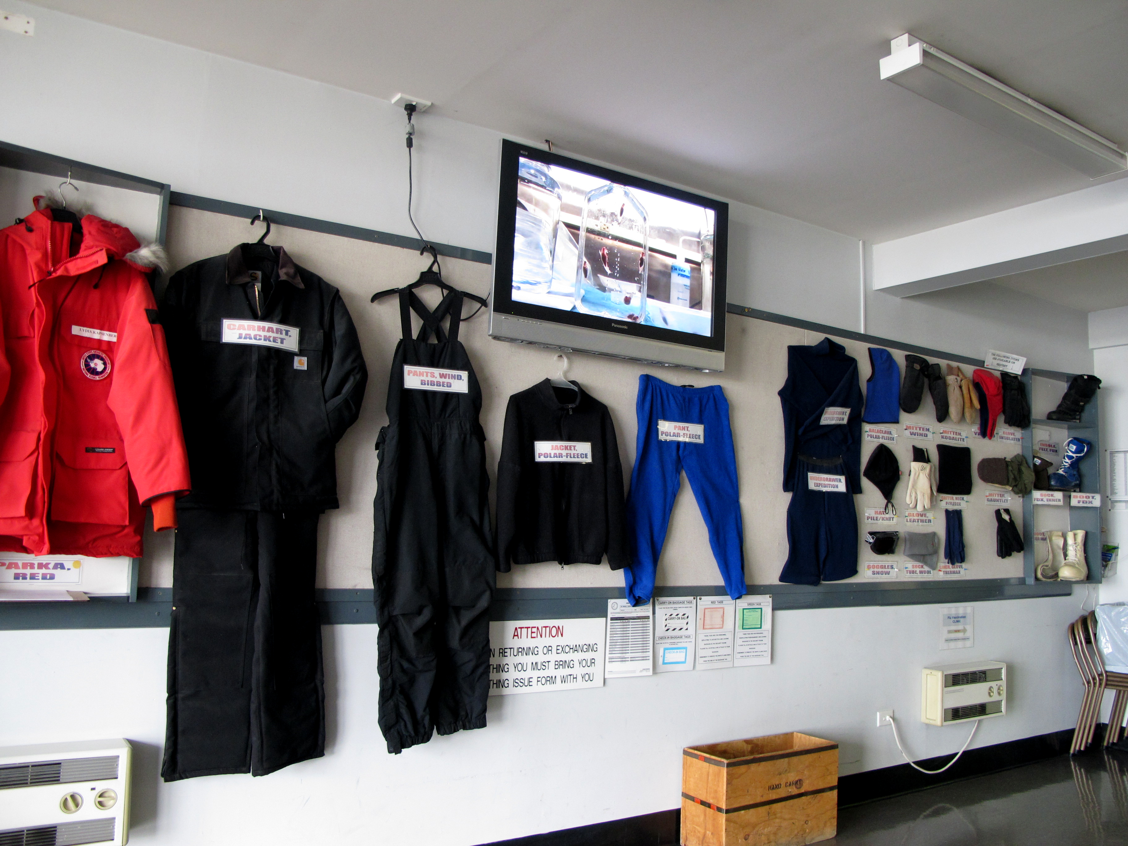 Clothes with signs hang on a wall.