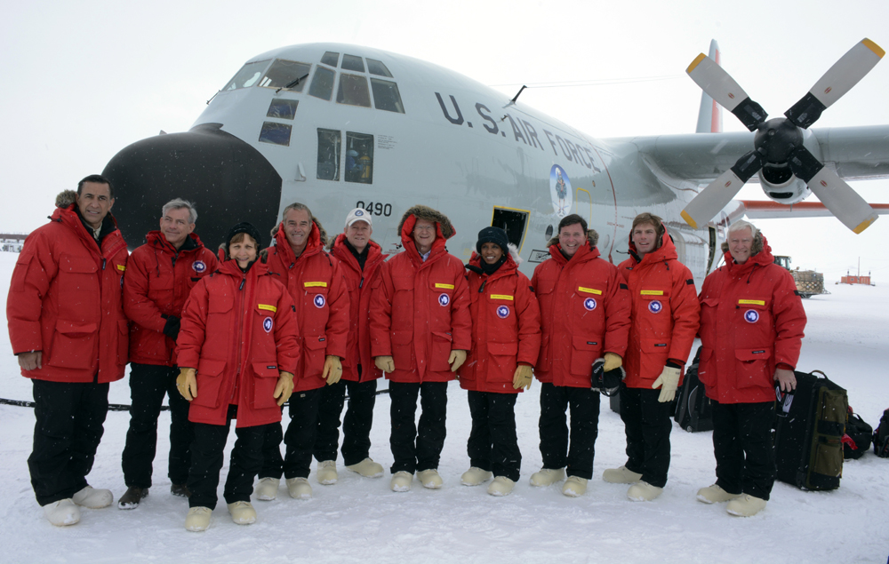 People pose in front of an airplane.