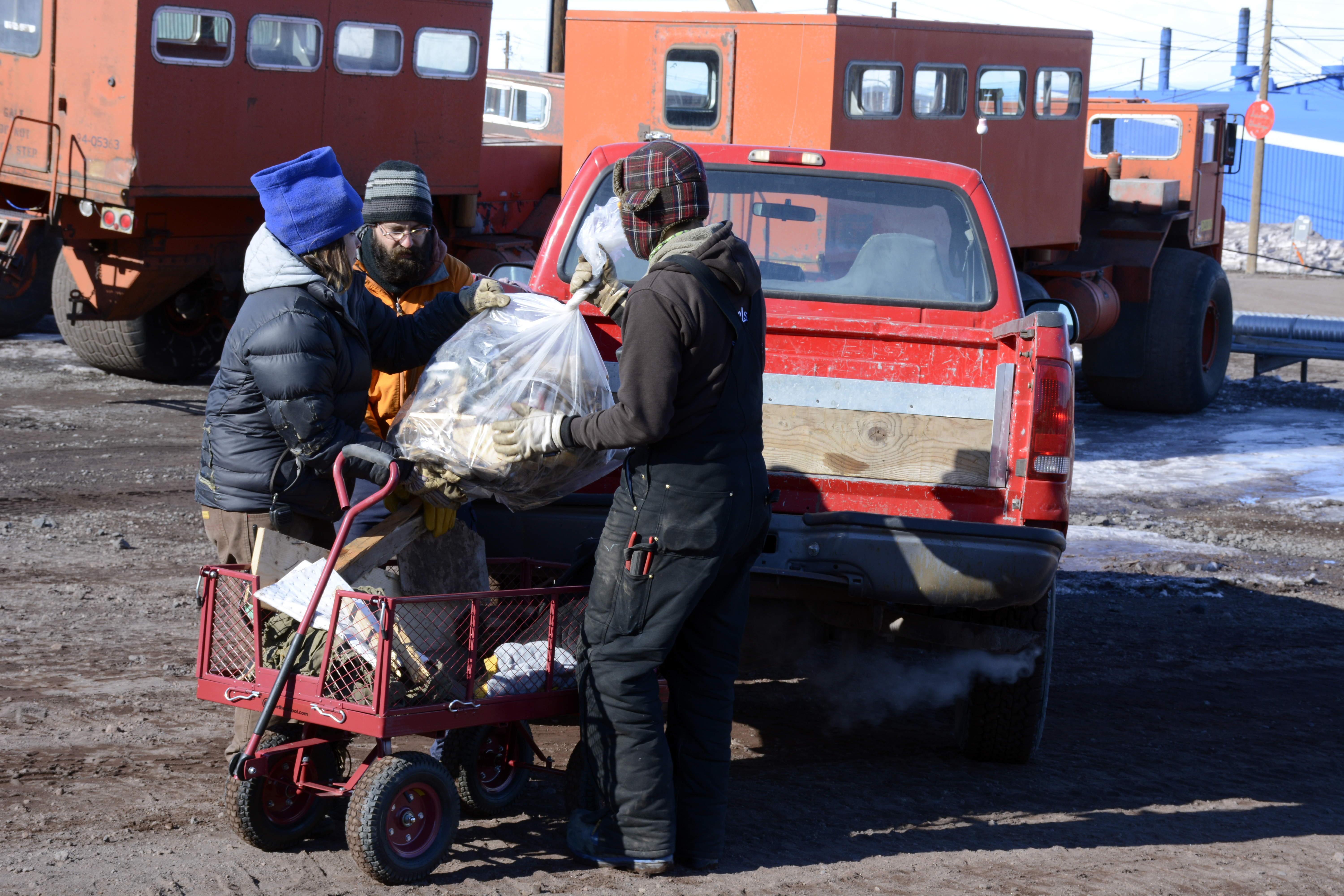 Several people load a plastic bag into a truck.