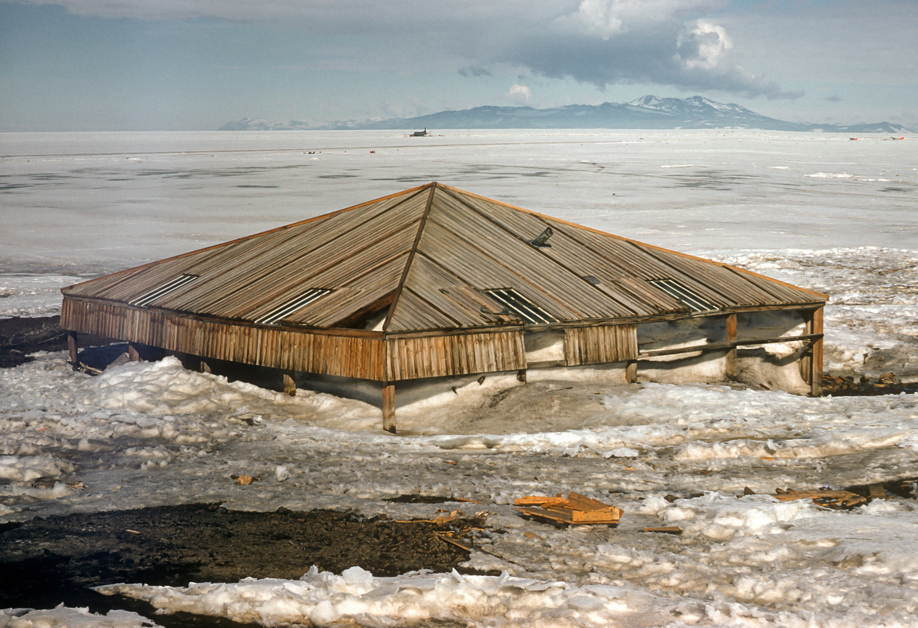 A now drifted building with mountains in the background.