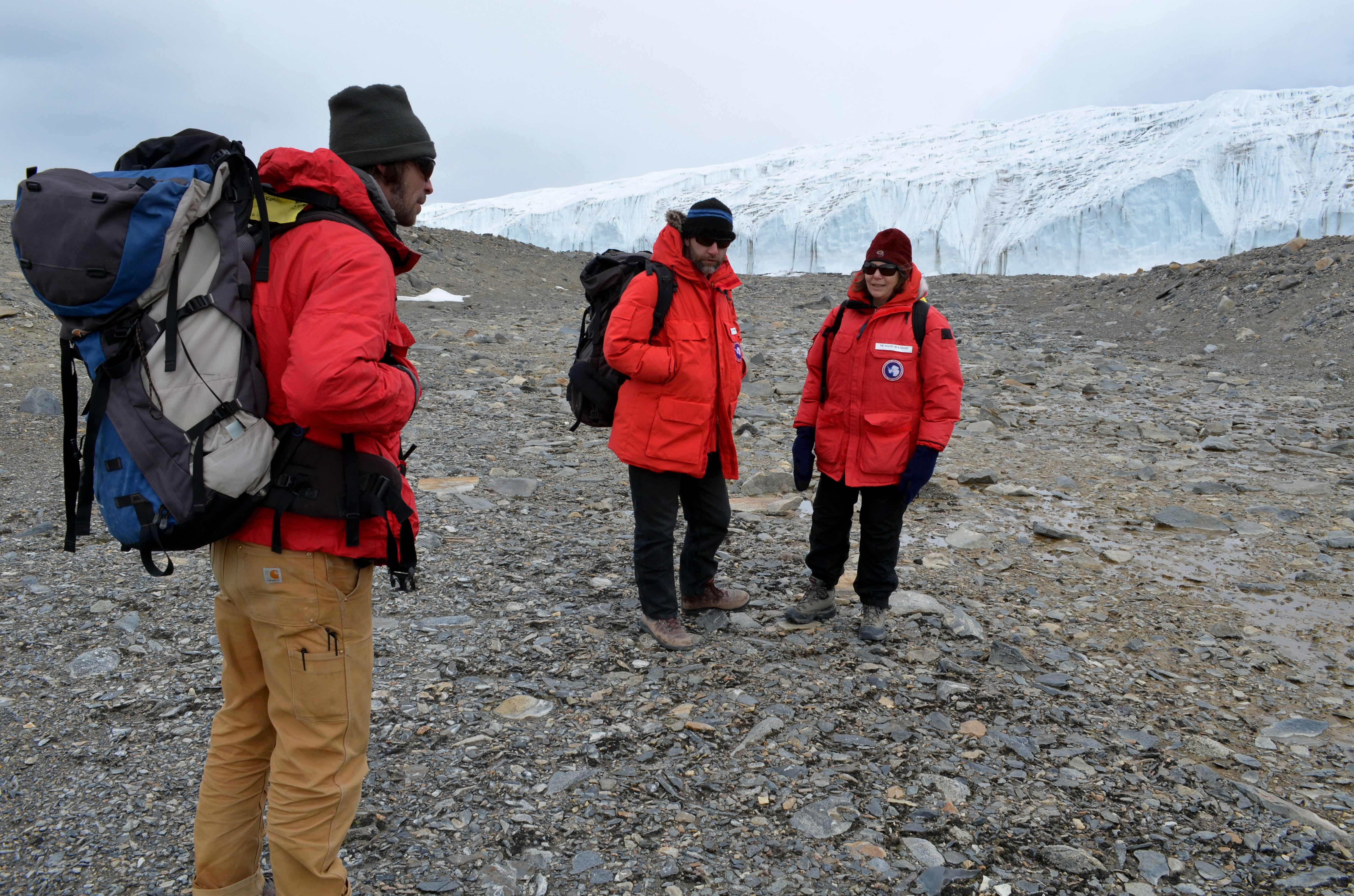 Three people hike through valley.