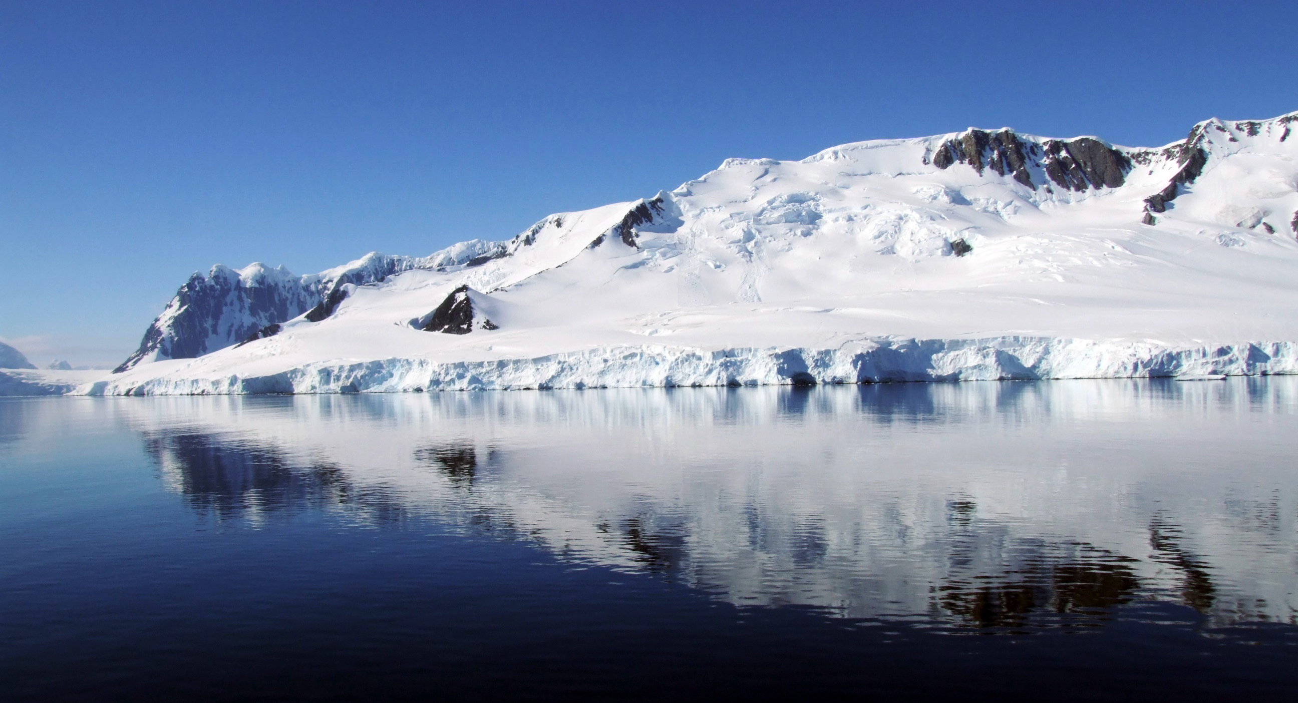 Glaciated mountain is reflected in calm water.