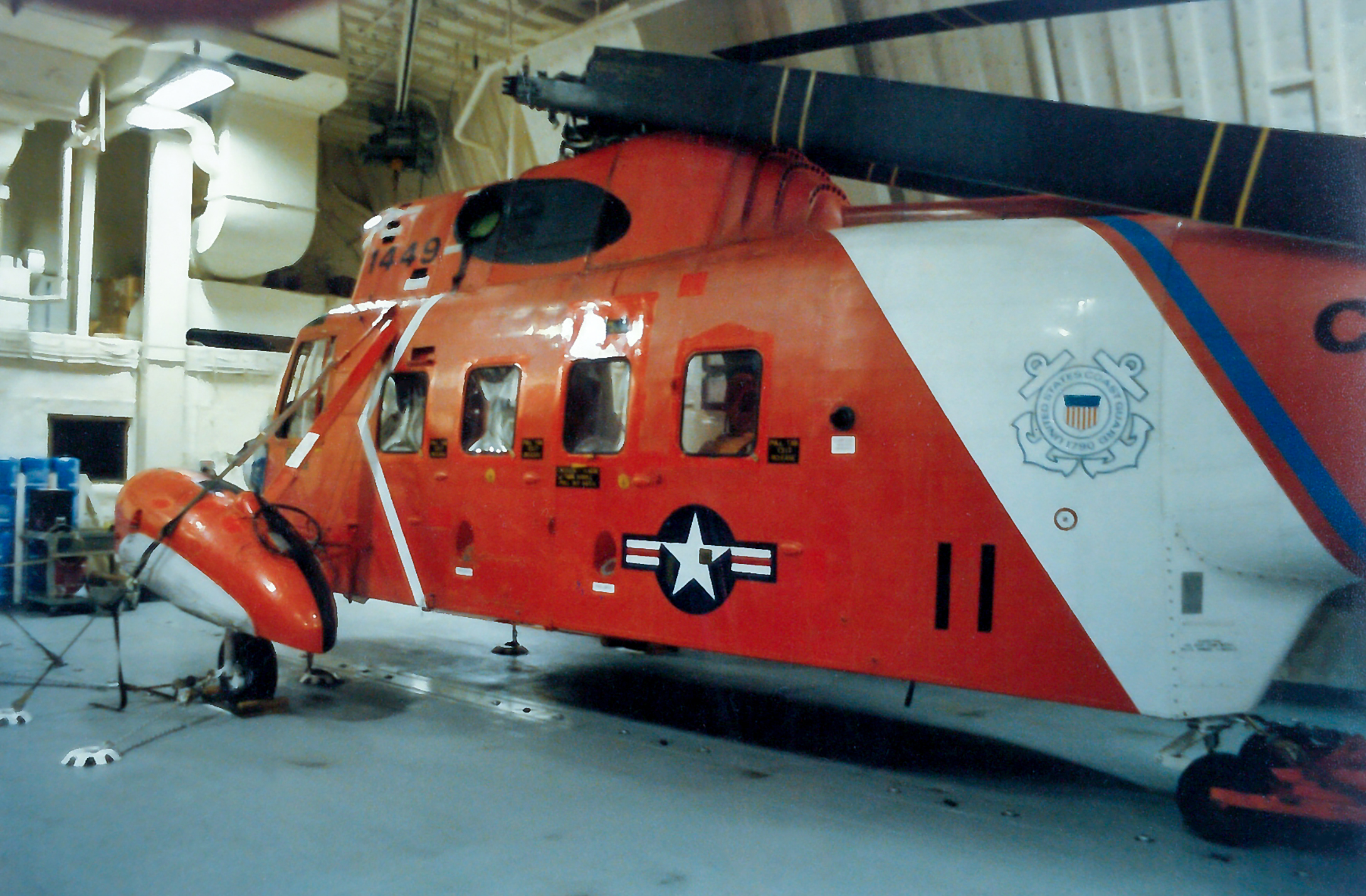 A red helicopter parked in a hanger.