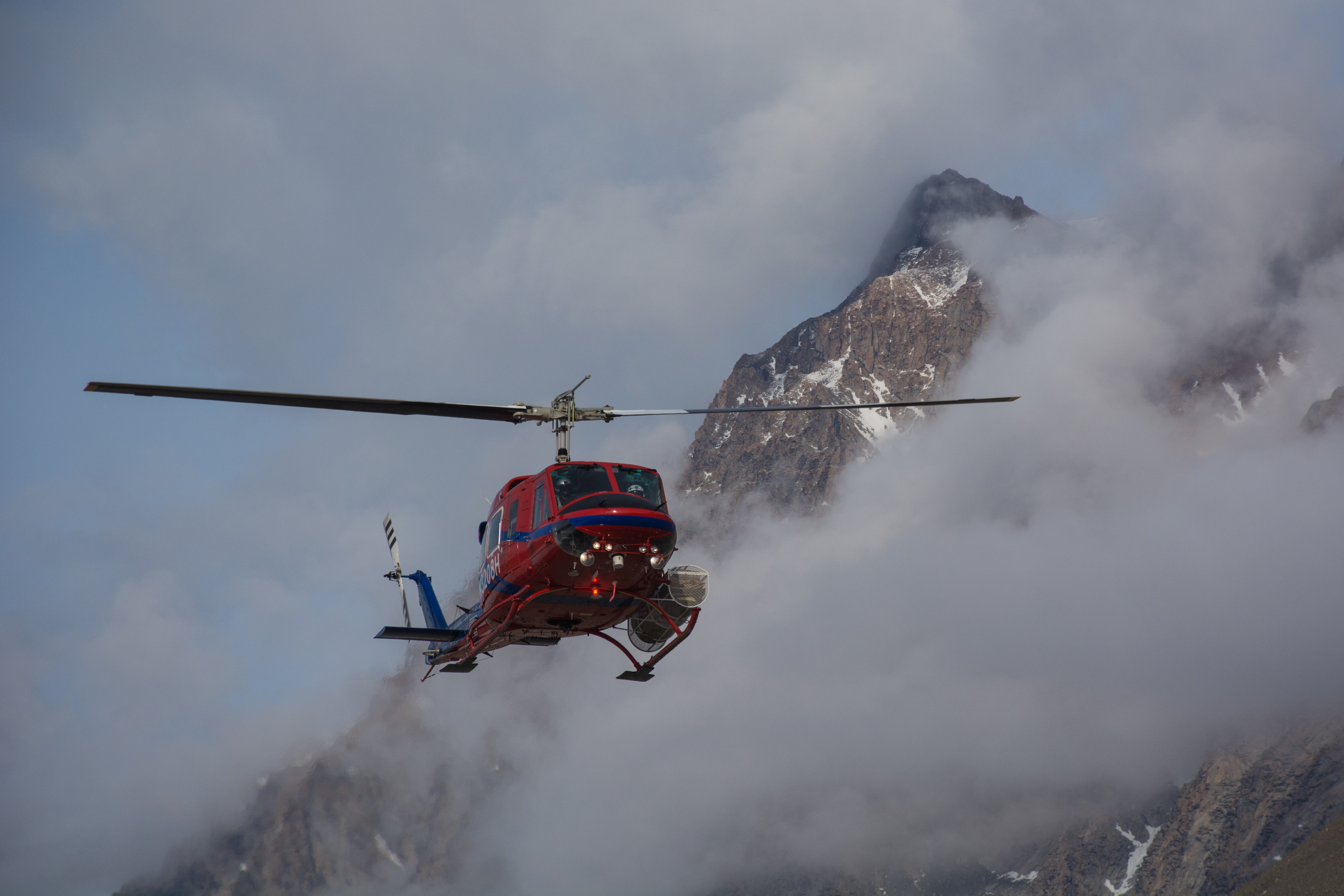 A helicopter comes in for a landing past hills and mist