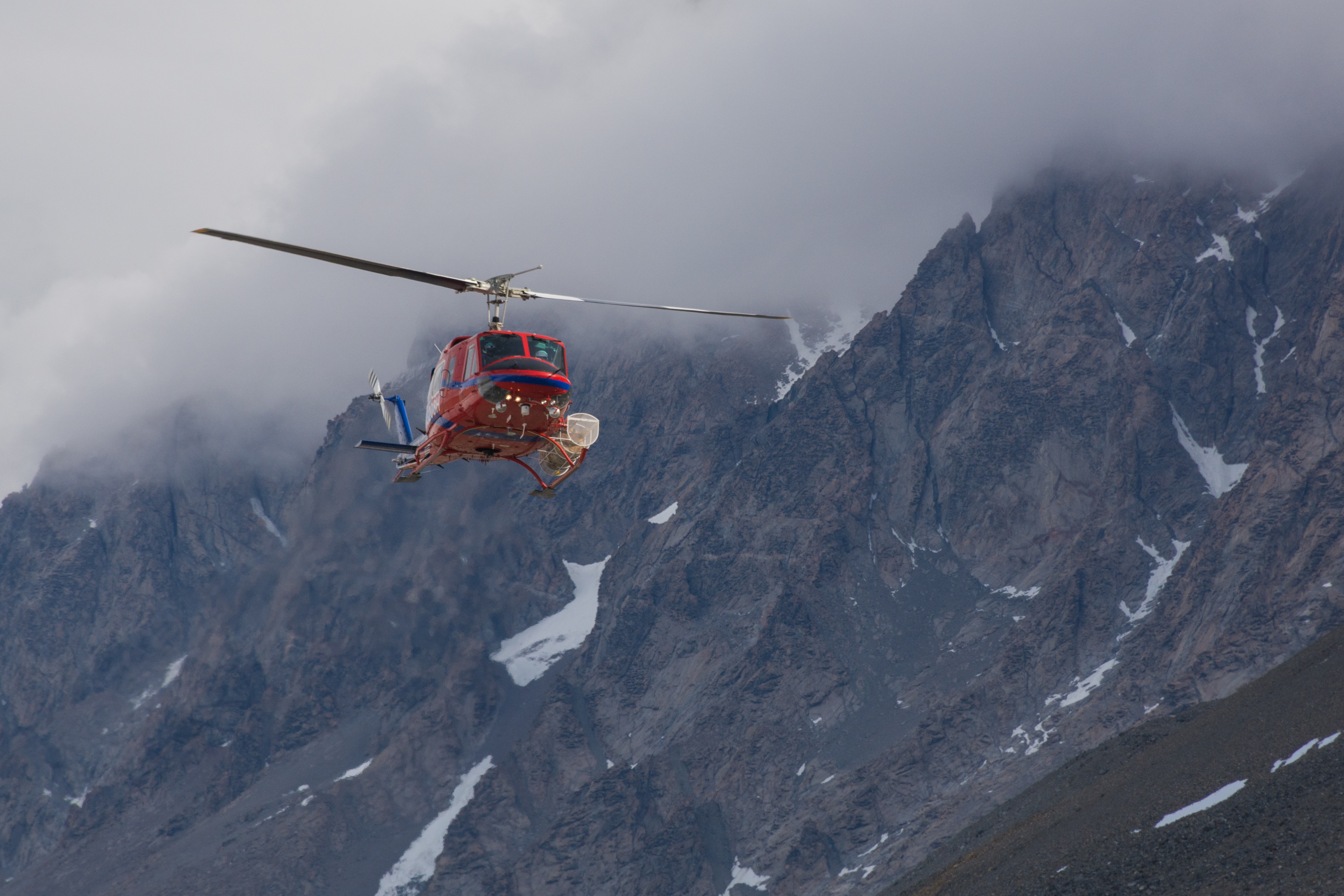 A helicopter comes in for a landing next to some hills and mist.