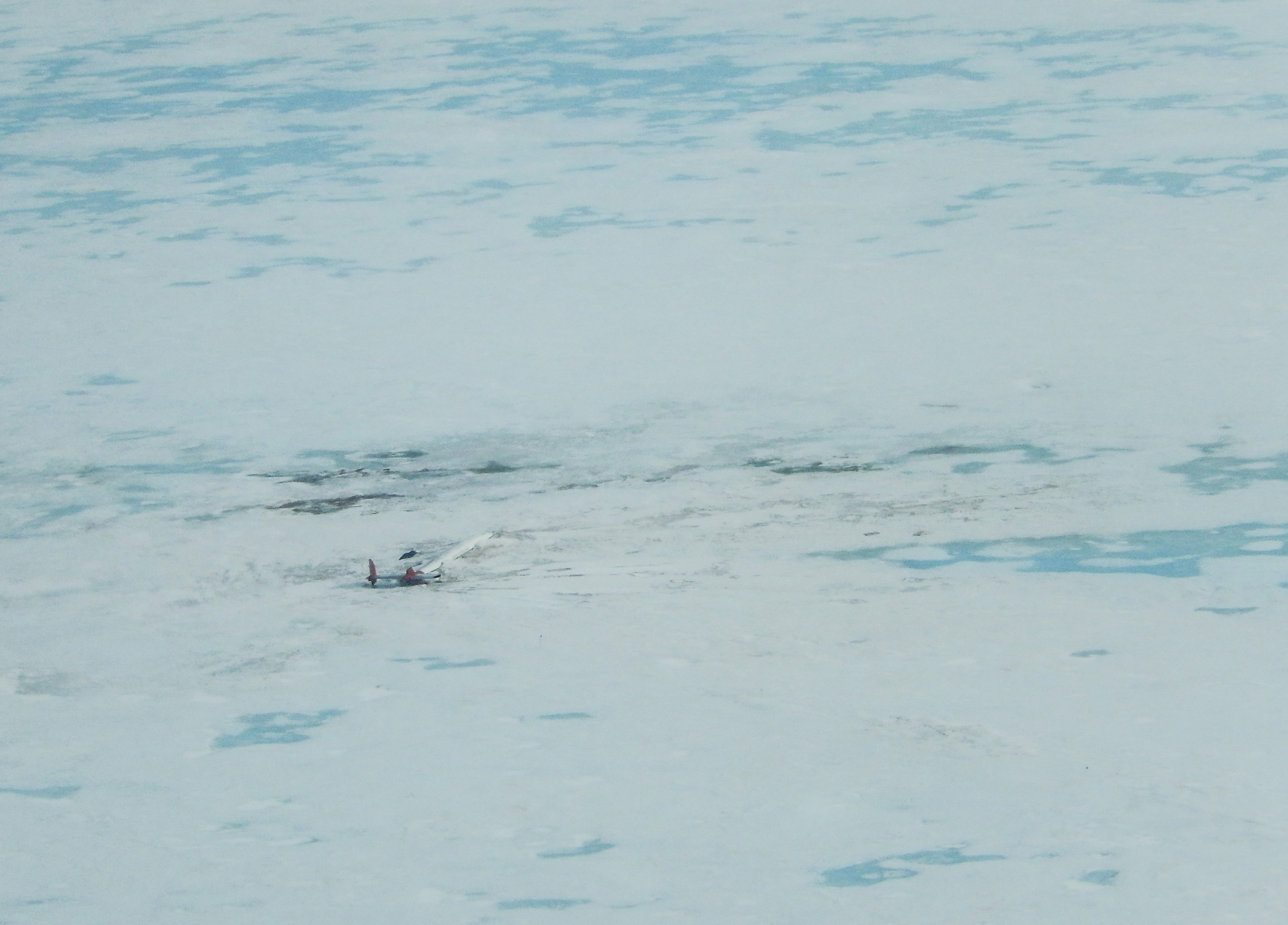 Aerial photo showing airplane buried in snow and ice.
