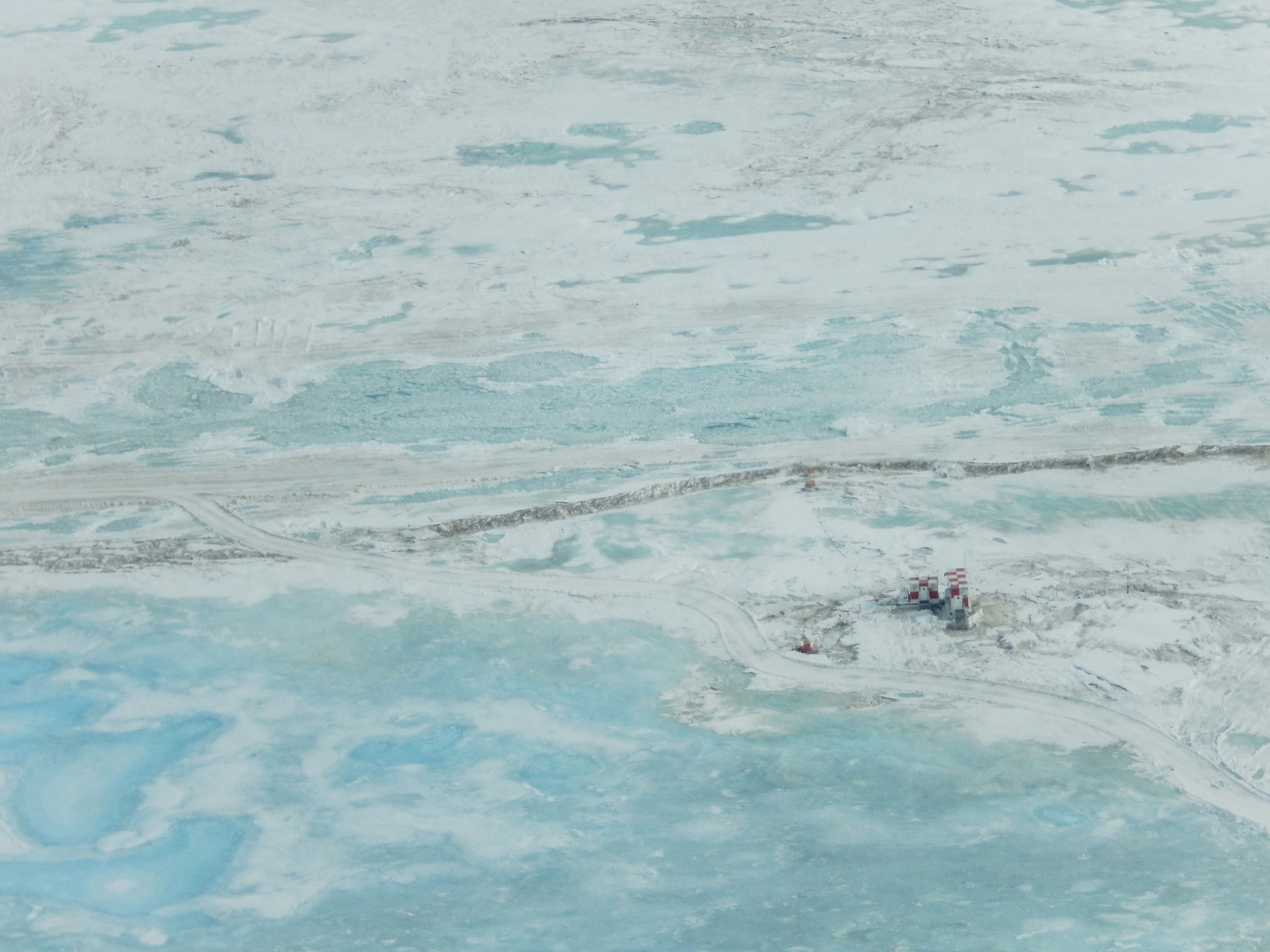 Aerial photo showing blue ice melt and buildings.
