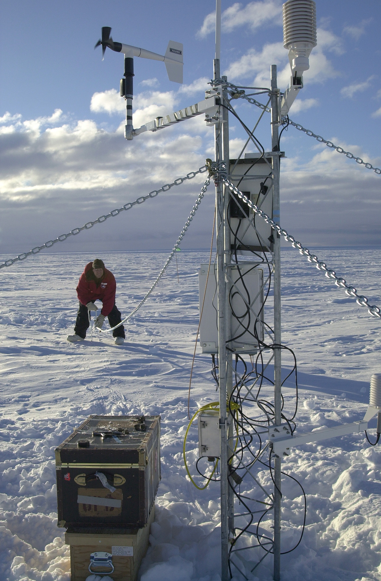 A person installs a cable on a tower.