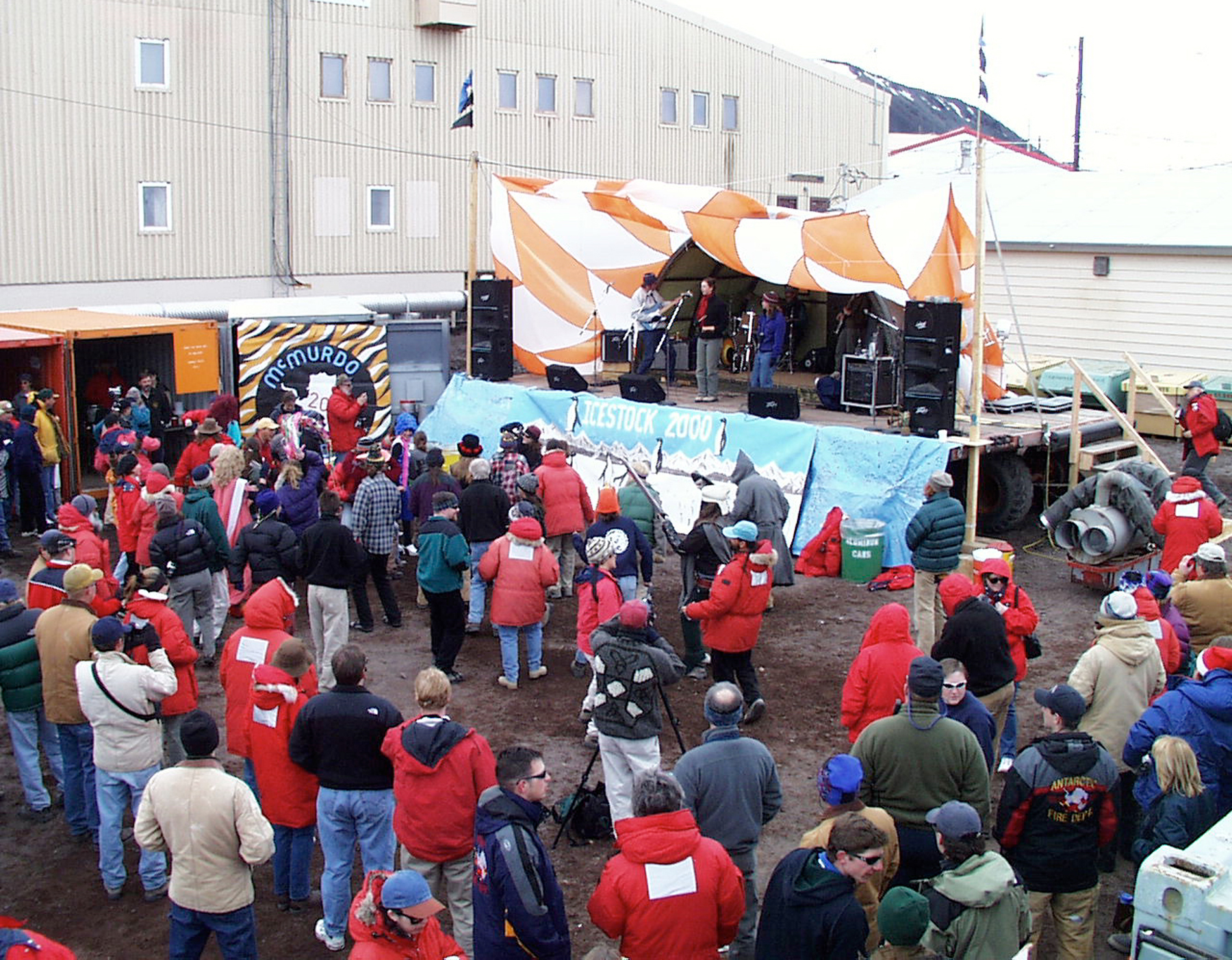 A crowd of people stand in front of a stage with musicians.