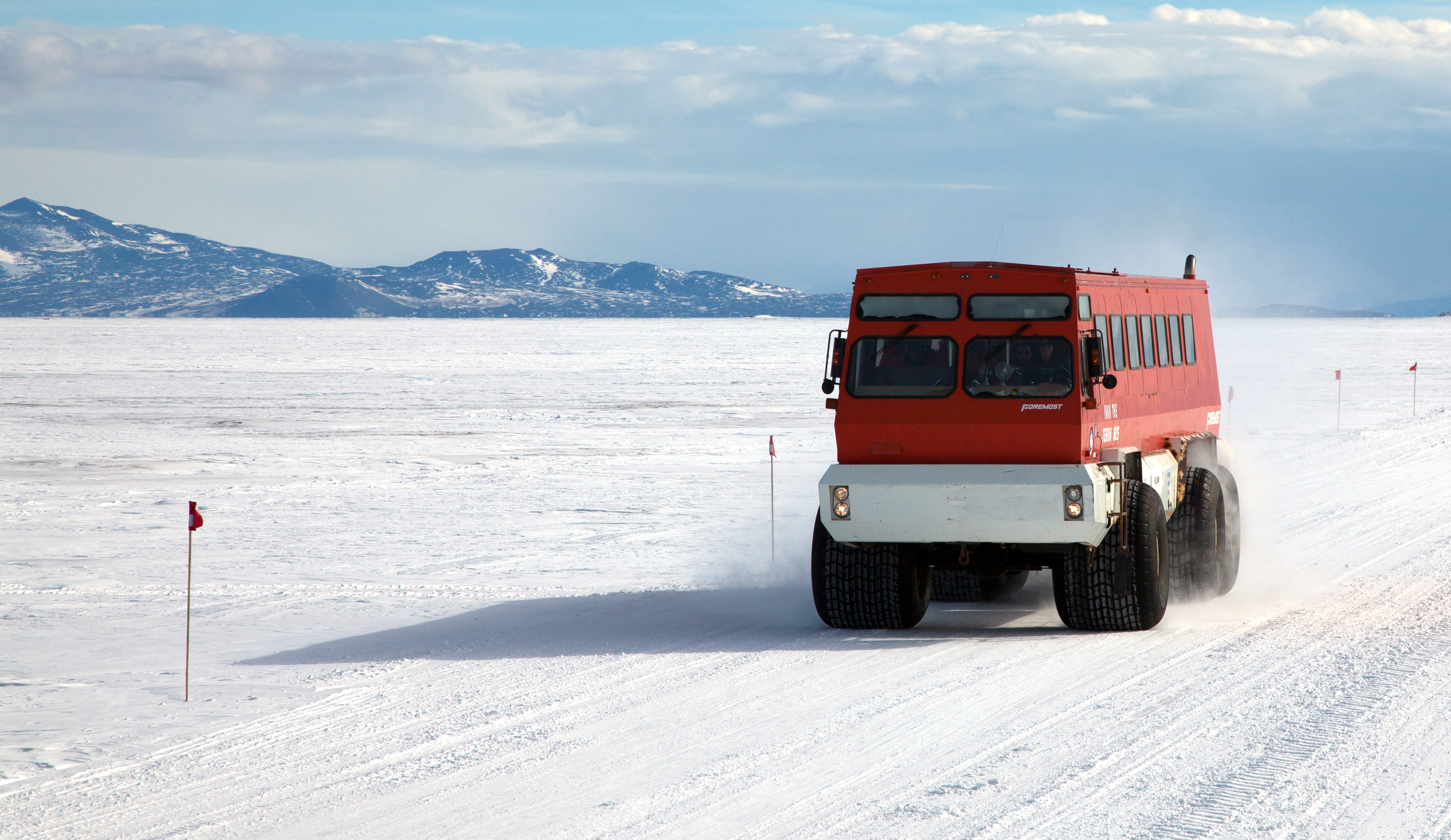 Red bus drives along snow road.