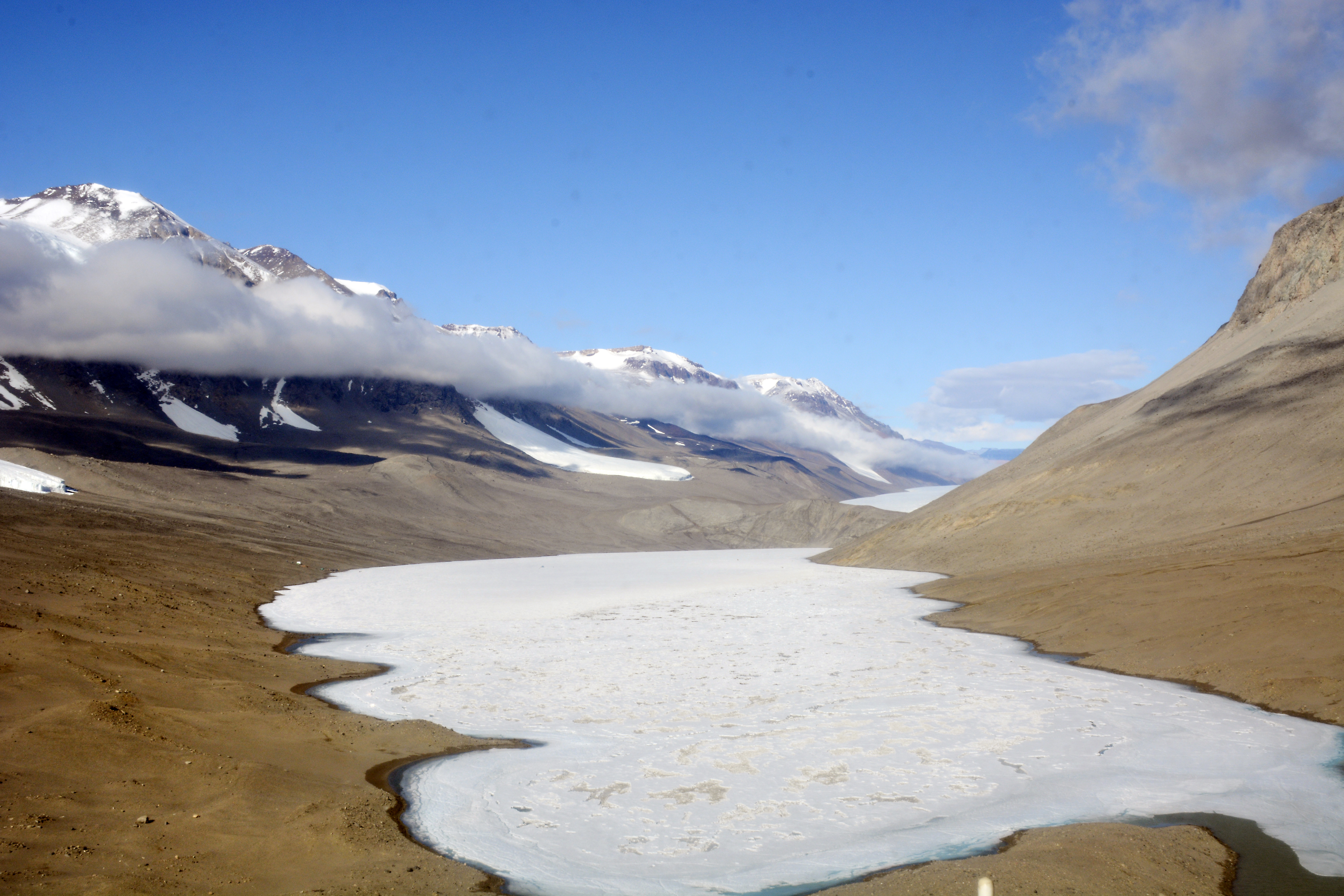 An ice-covered lake sits in a barren valley.