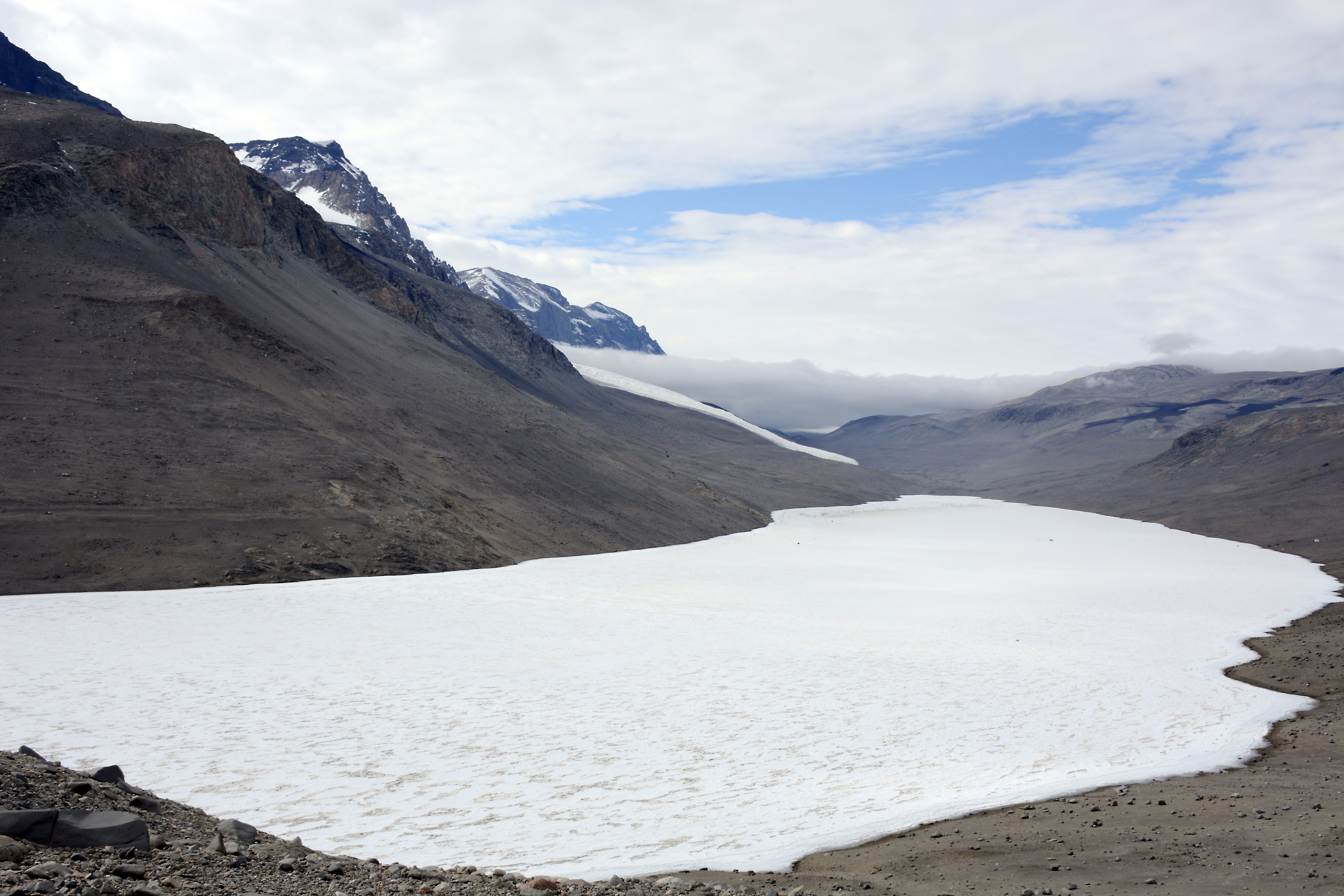 An ice-covered lake sits in a barren valley.