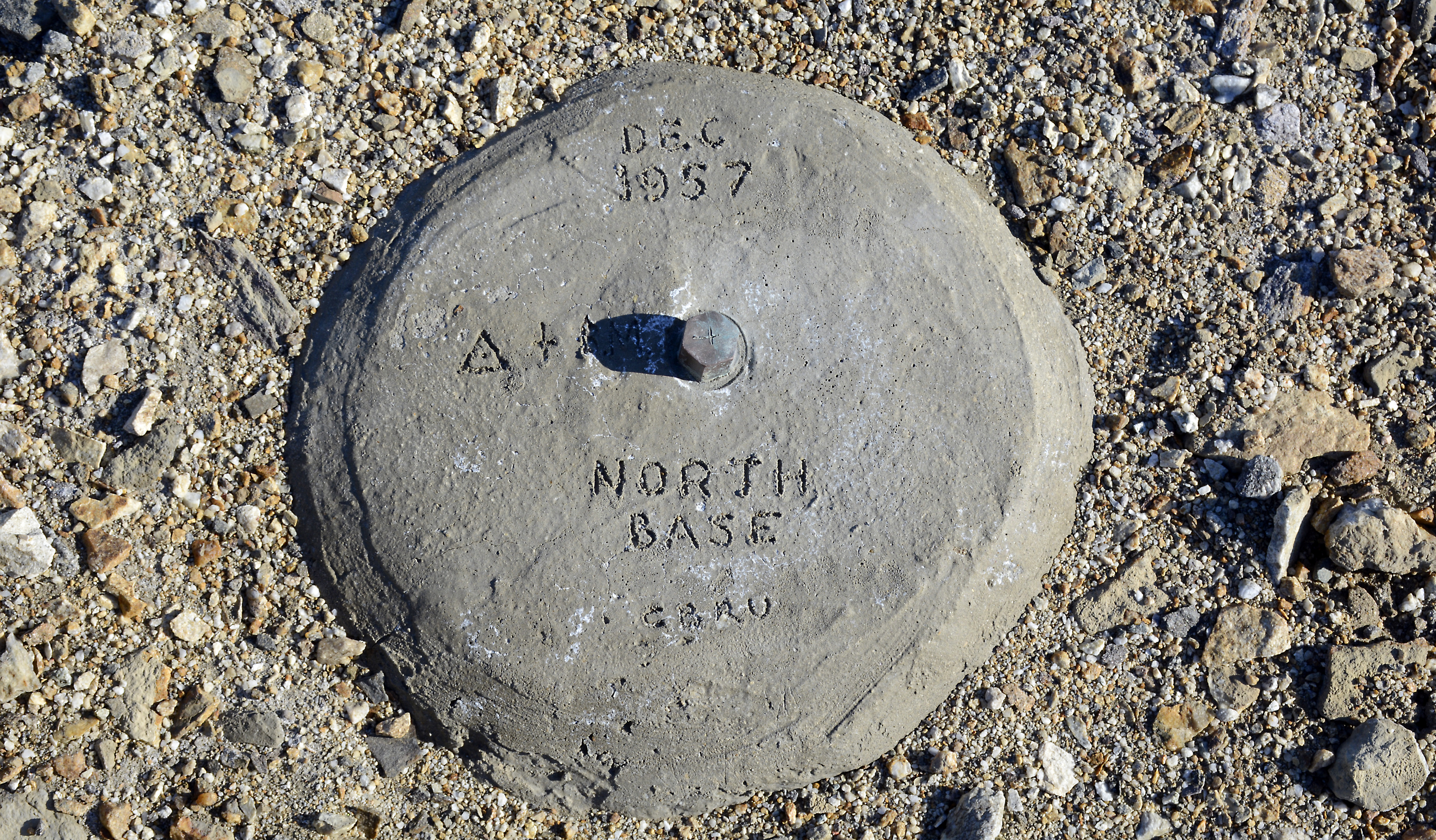 A geographic marker sits in the dirt.