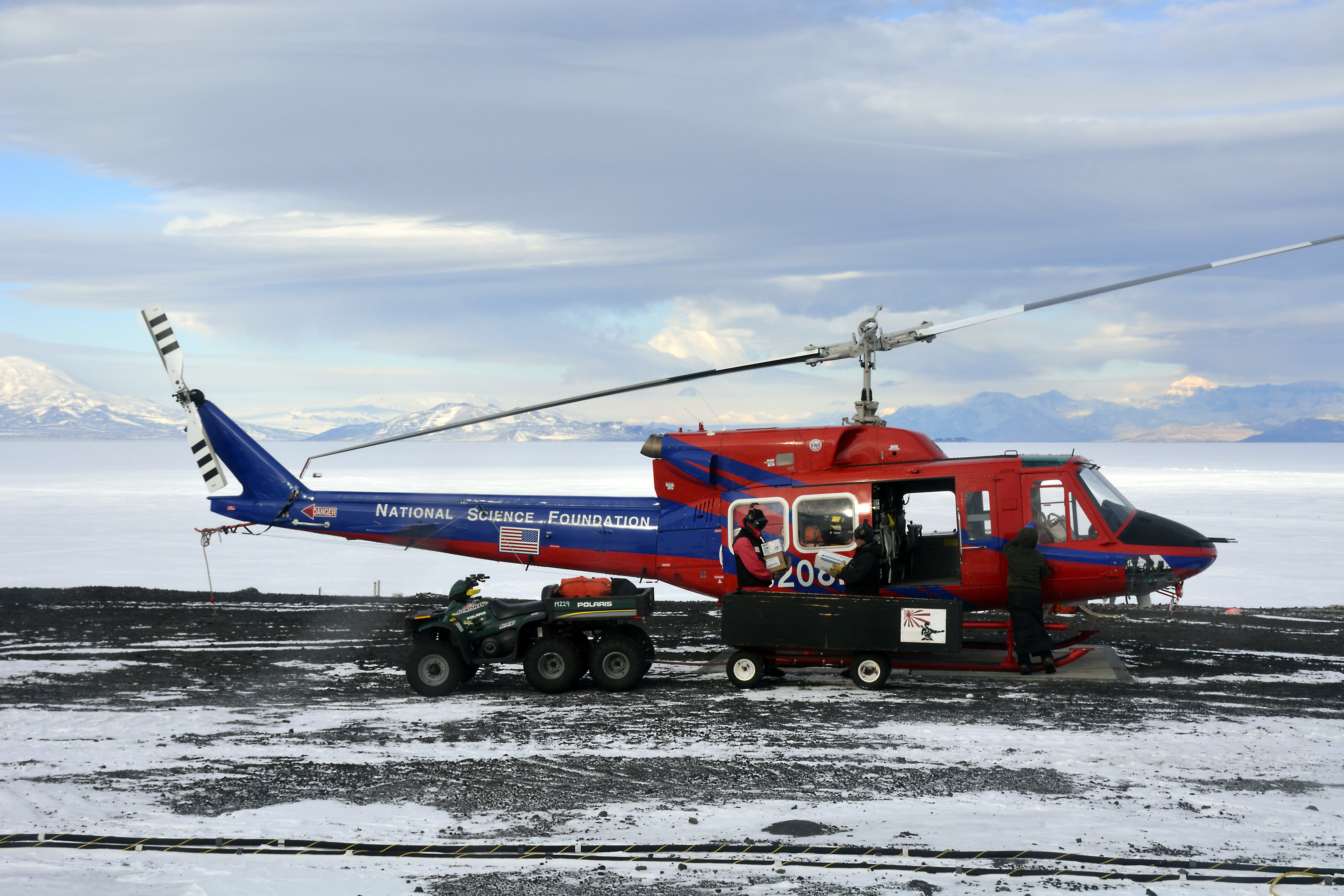 People load cargo onto a helicopter.