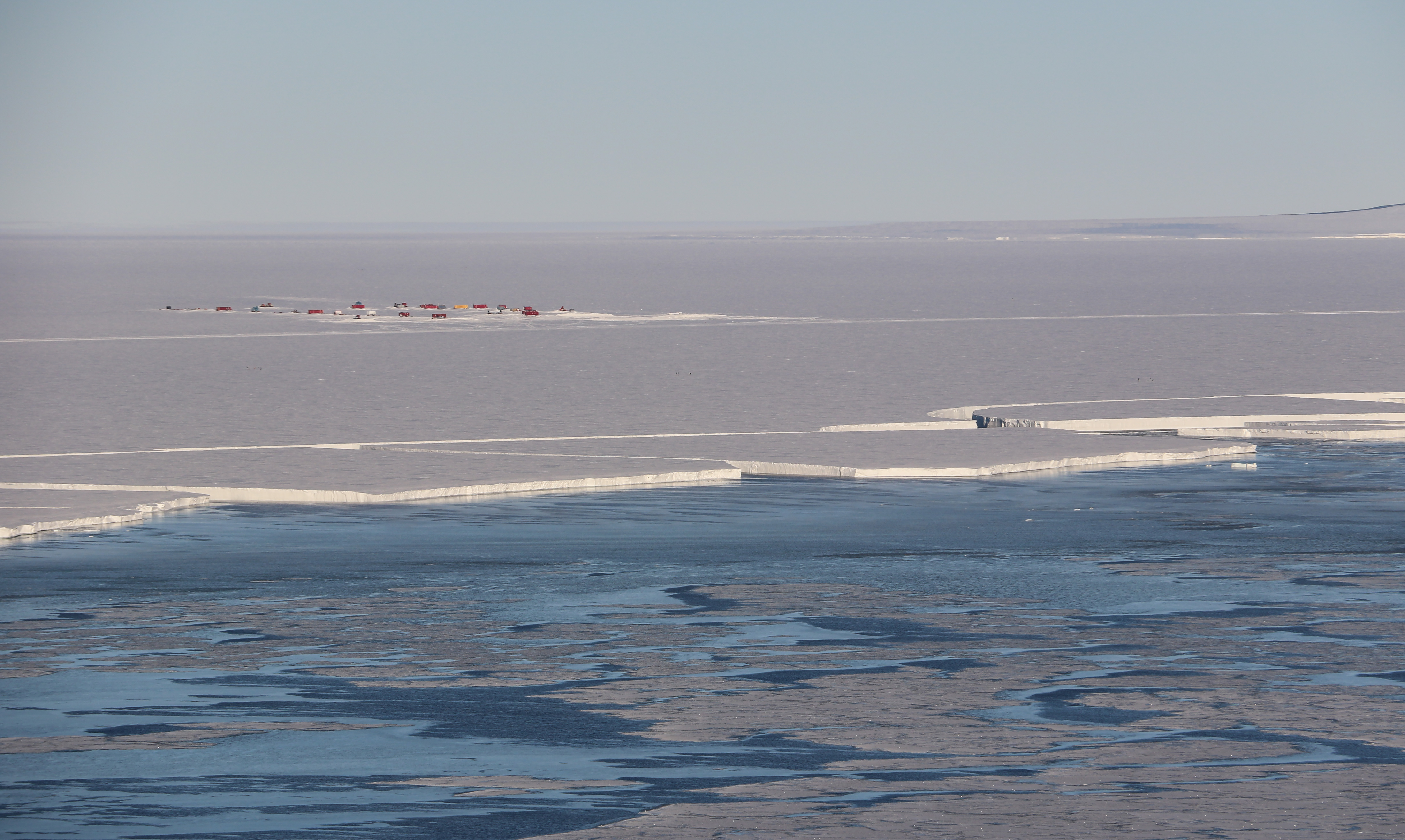 Aerial panoramic photo showing open water and ice sheets.
