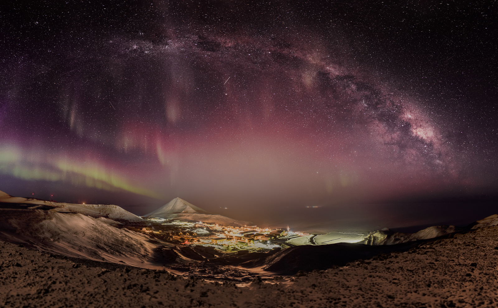 A view of a town at night with auroras.