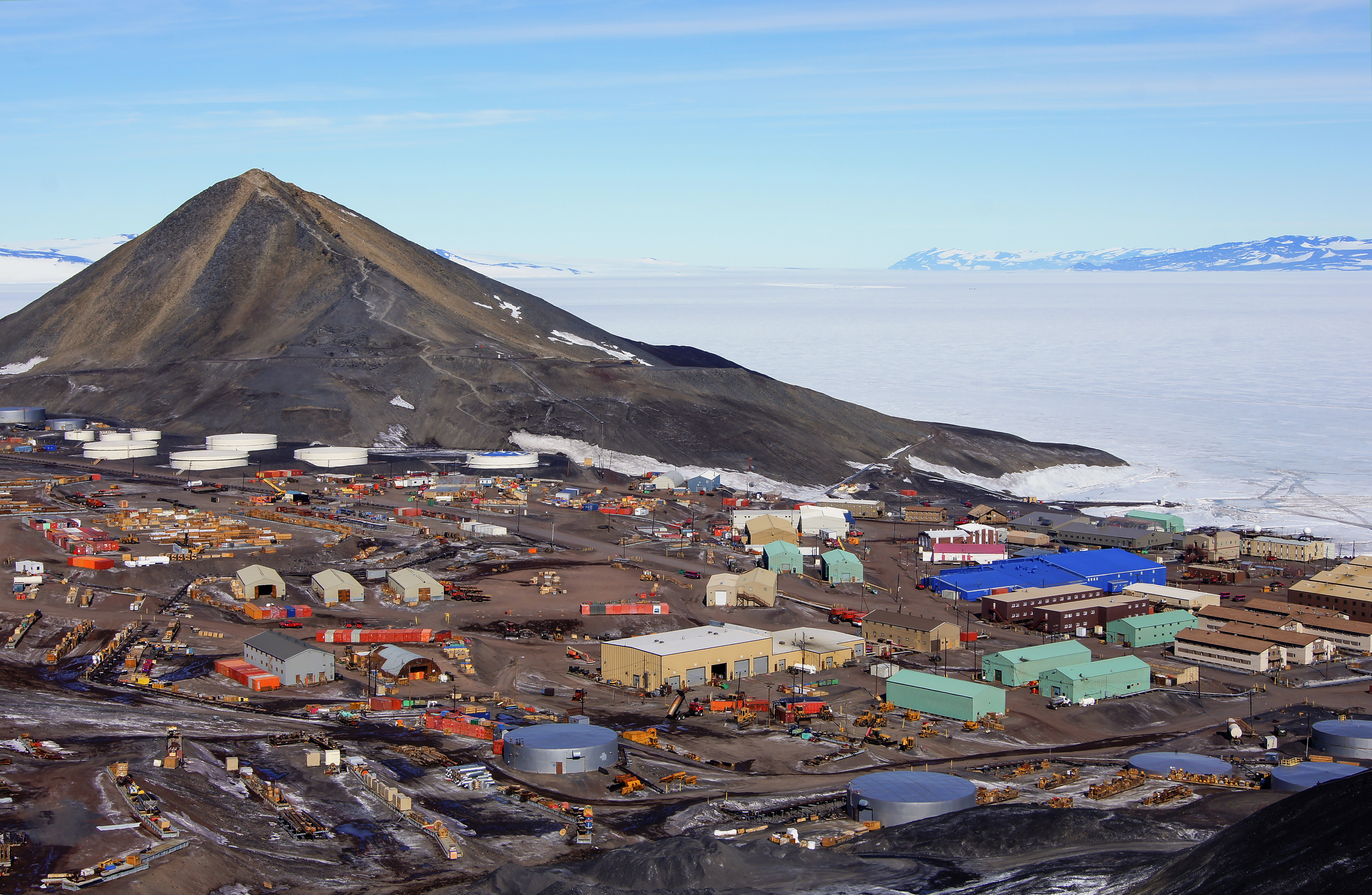 A photo of a town with a hill behind it.