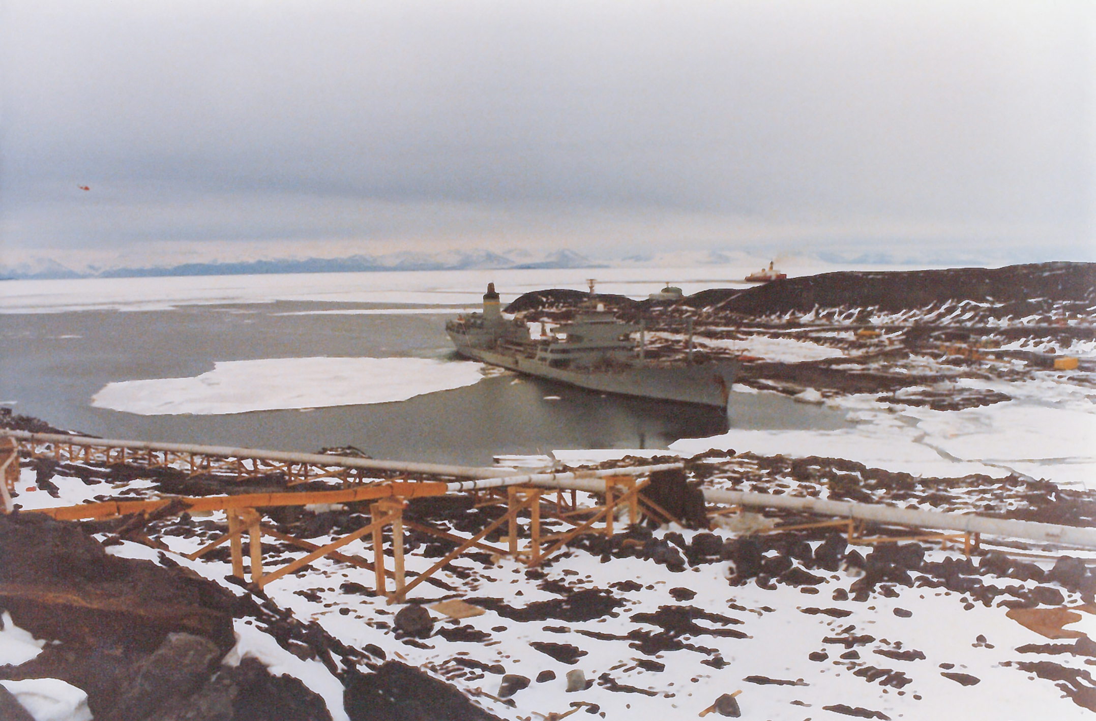 A gray vessel docked in sea ice.