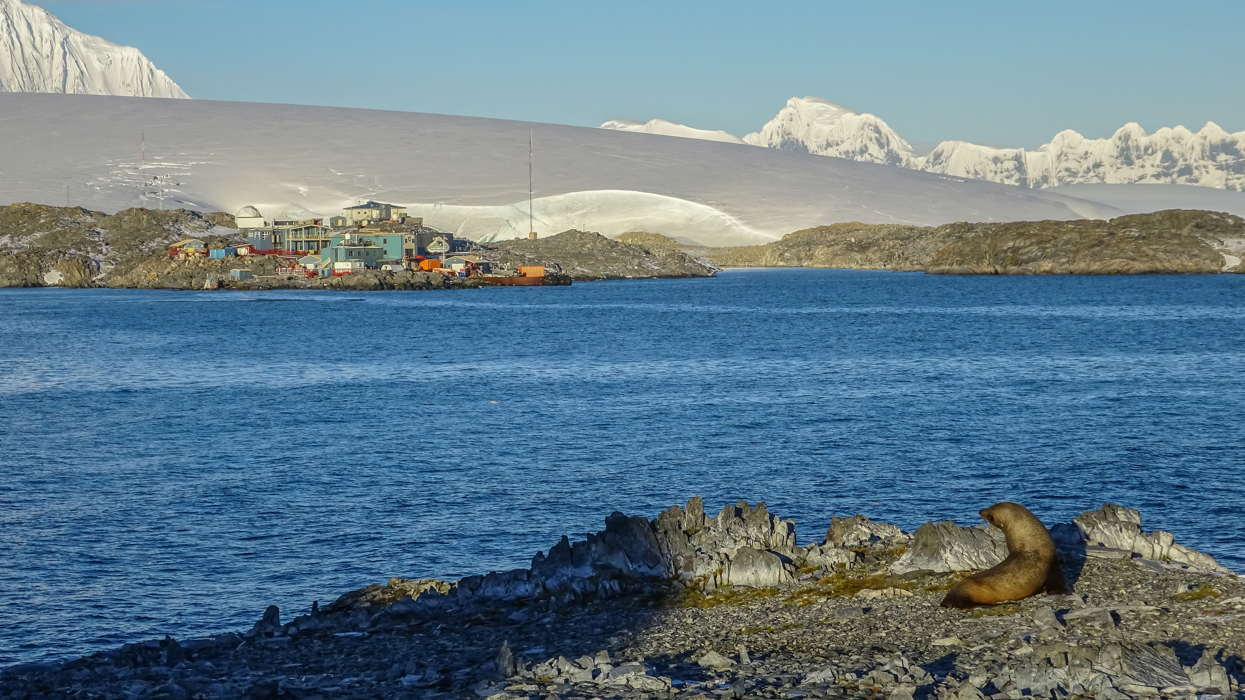 A view of a small station below a glacier and mountains.