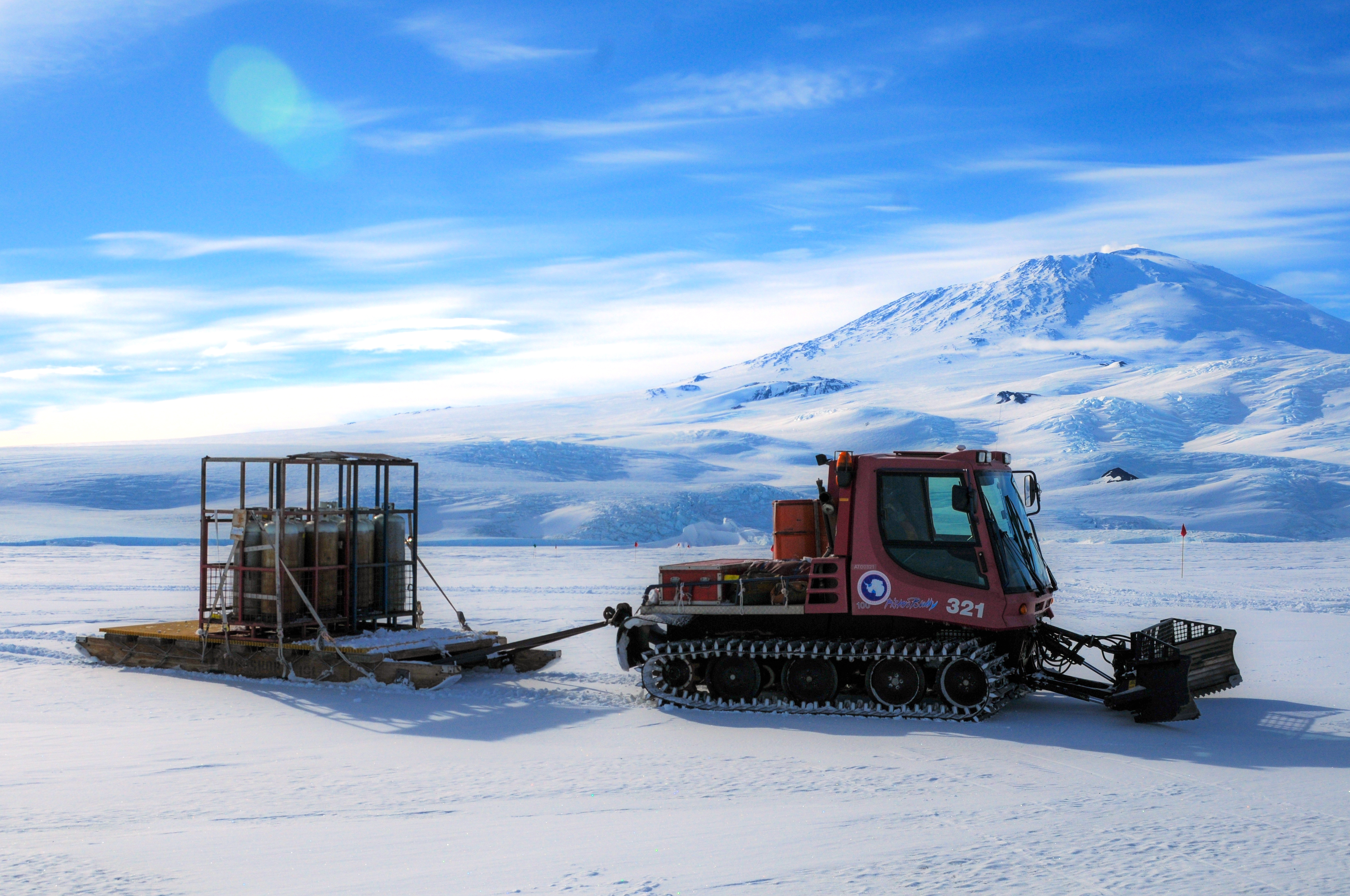 Vehicle with tracks pulls sled of cargo.