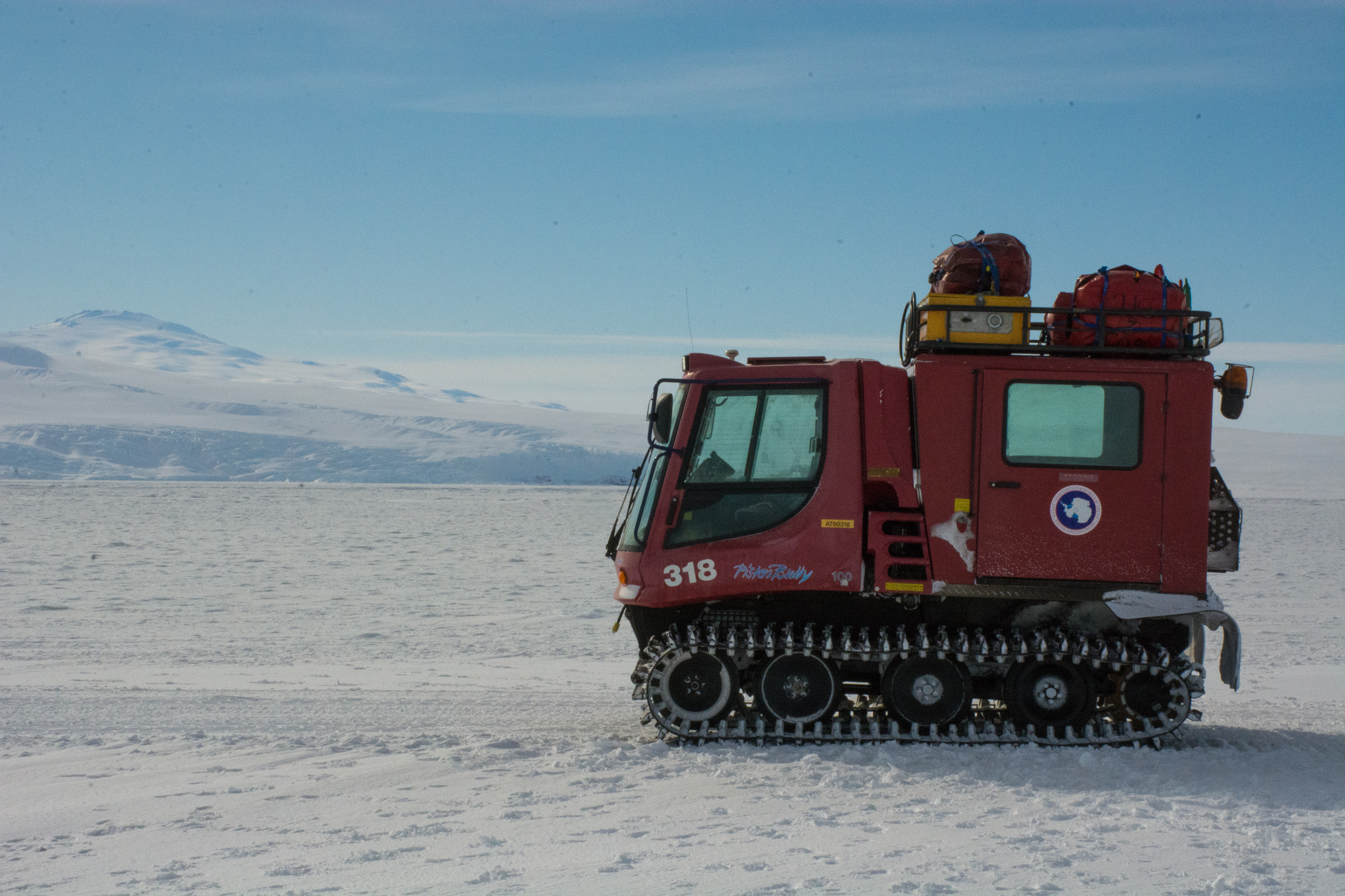 A small, red vehicle is parked on ice.