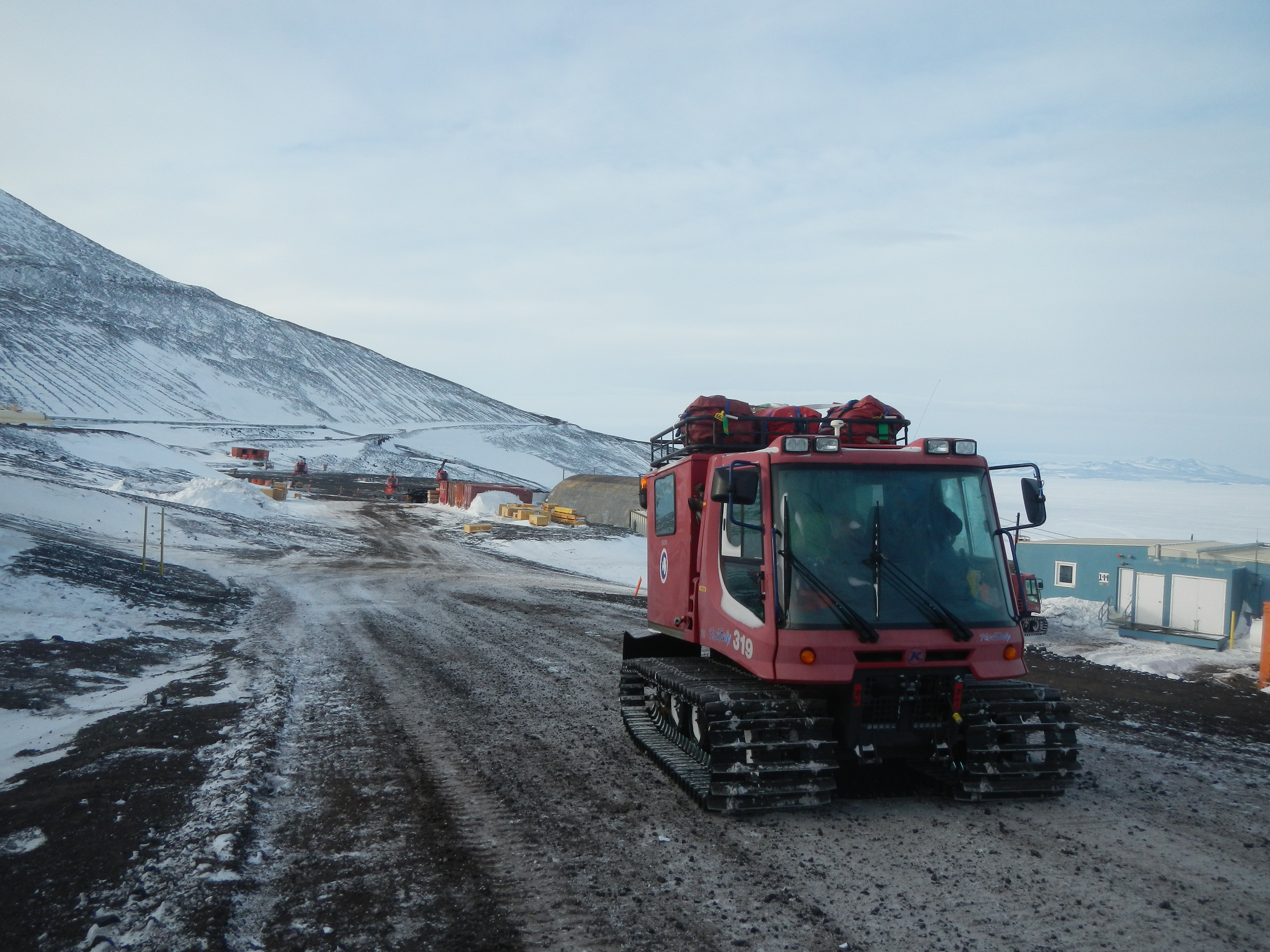 A tracked vehicle drives up a gravel road.