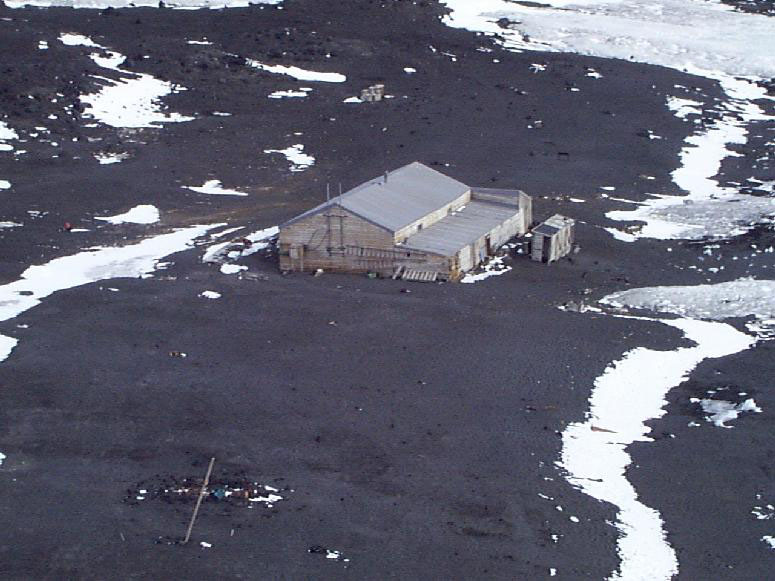 Aerial view of a wooden hut sitting on rocky terrain.