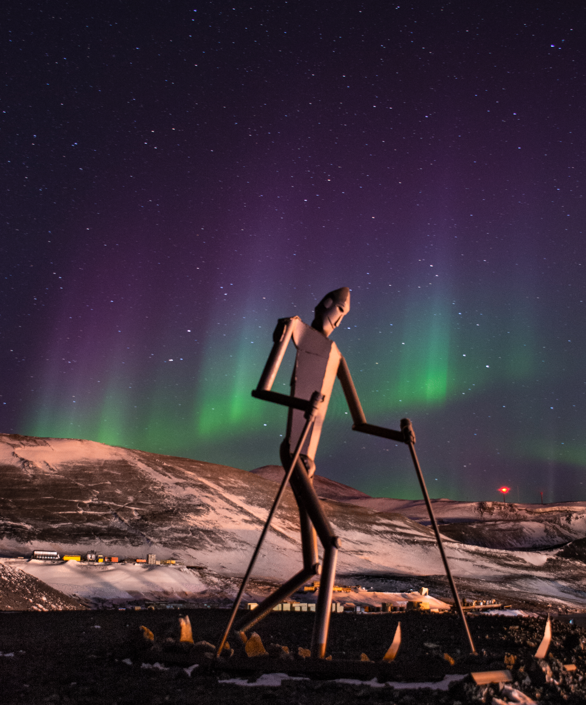 A sculpture of a skier is illuminated against the night sky.