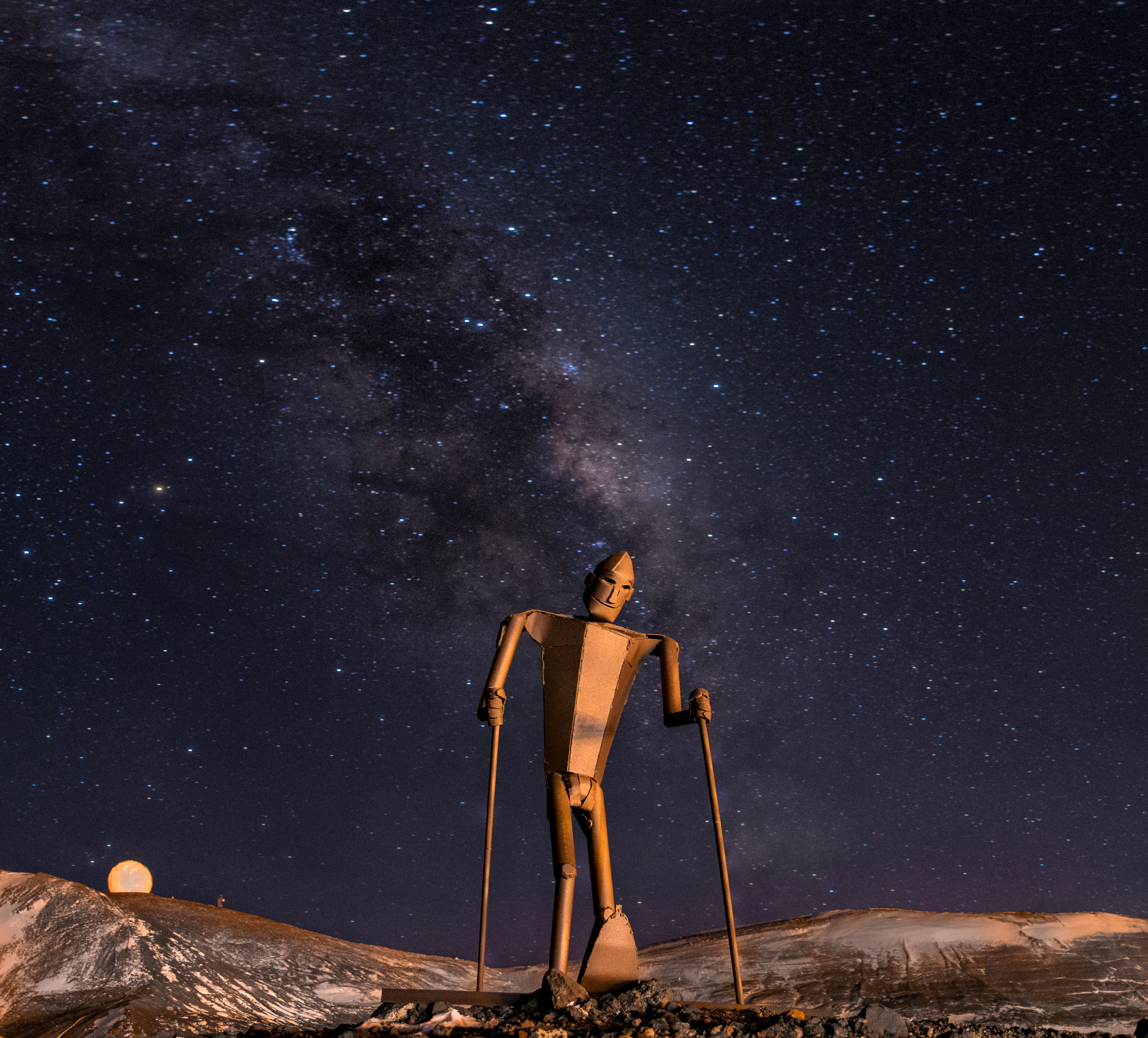 A sculpture of a skier is illuminated against the night sky.