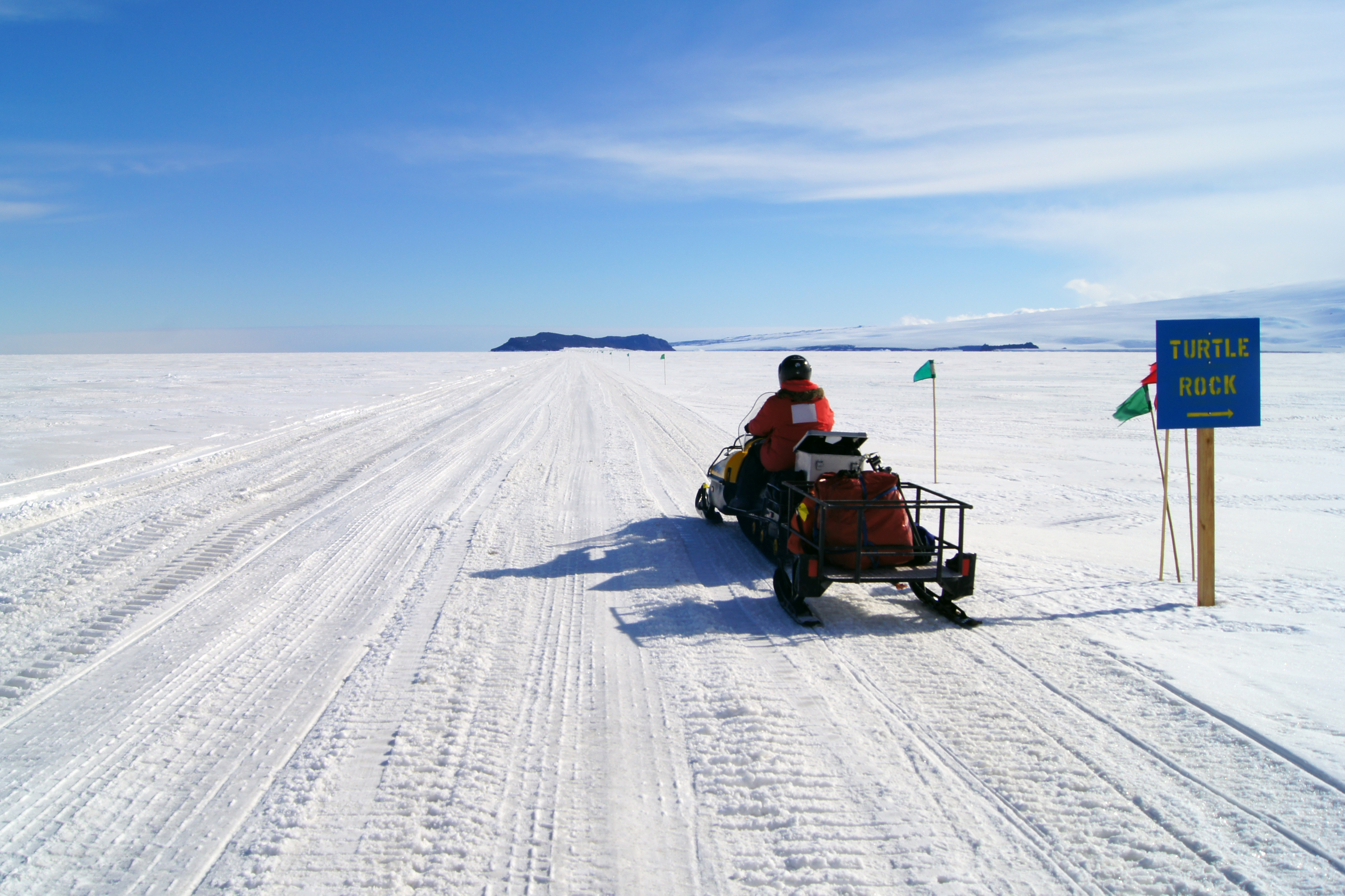 A snowmobile drives down a snow road. 