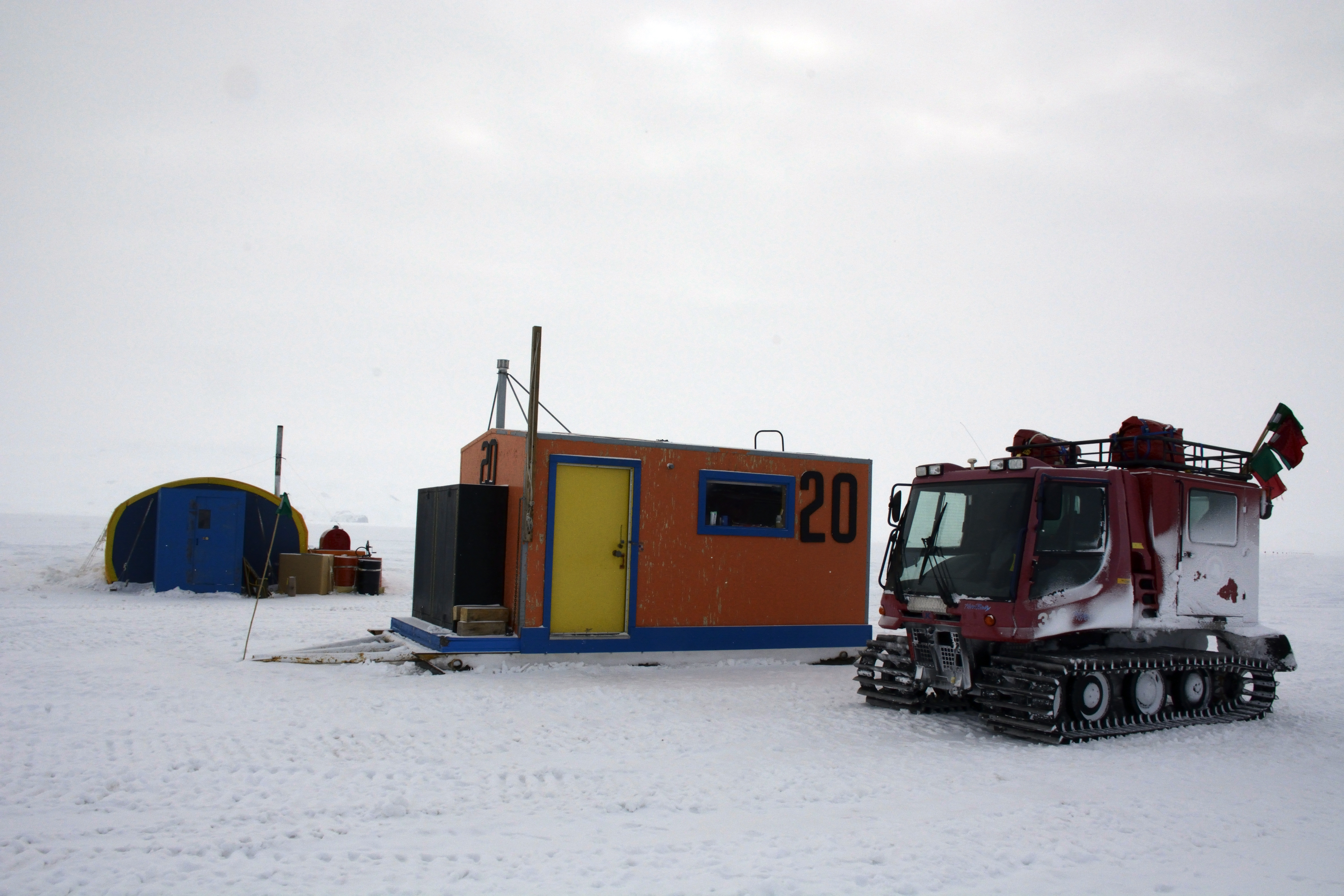 A vehicle is parked in front of a small, orange building.