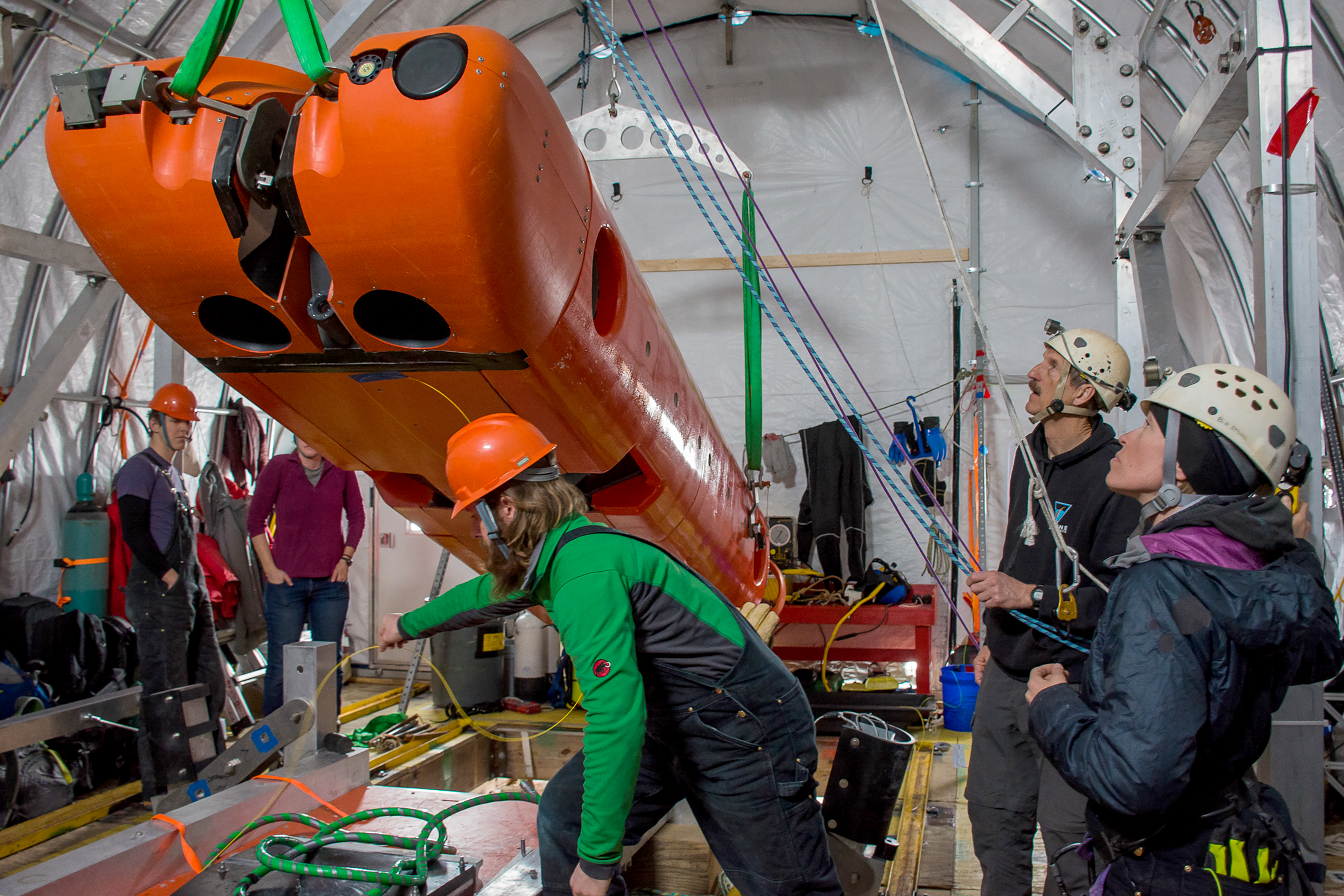 Person holding cables for big orange machine.