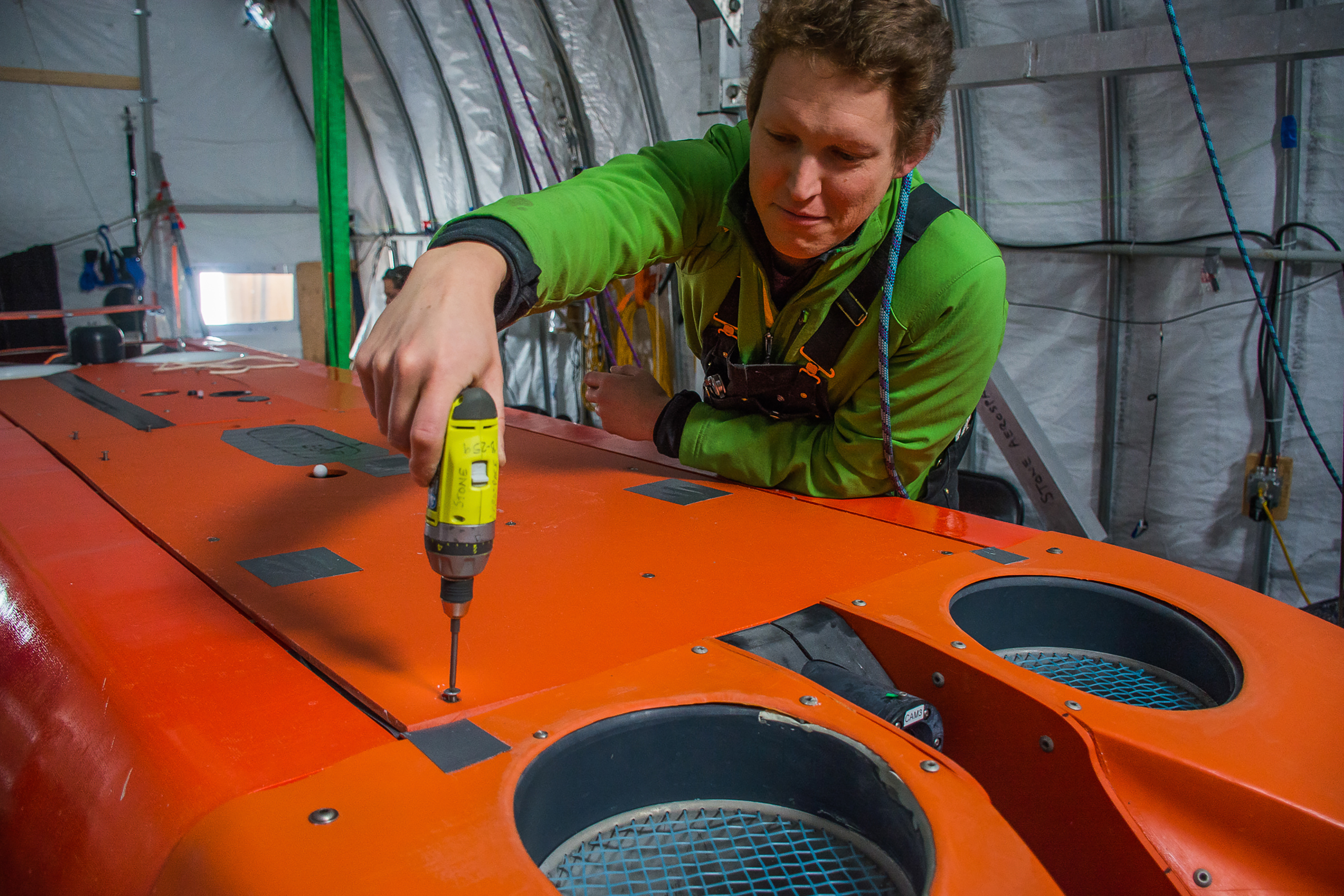 A person fixing an orange machine.