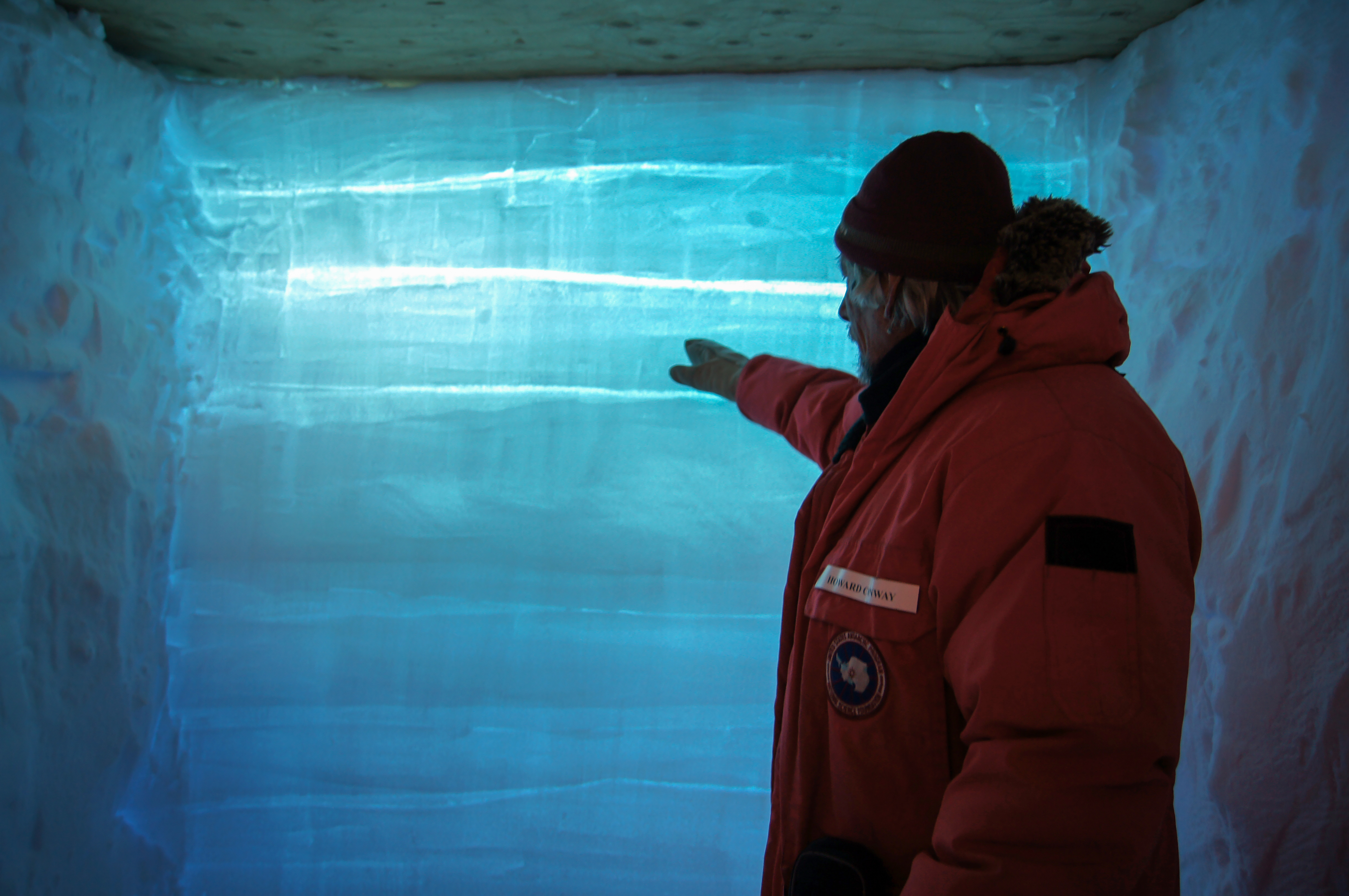 A man pointing at blue snow.