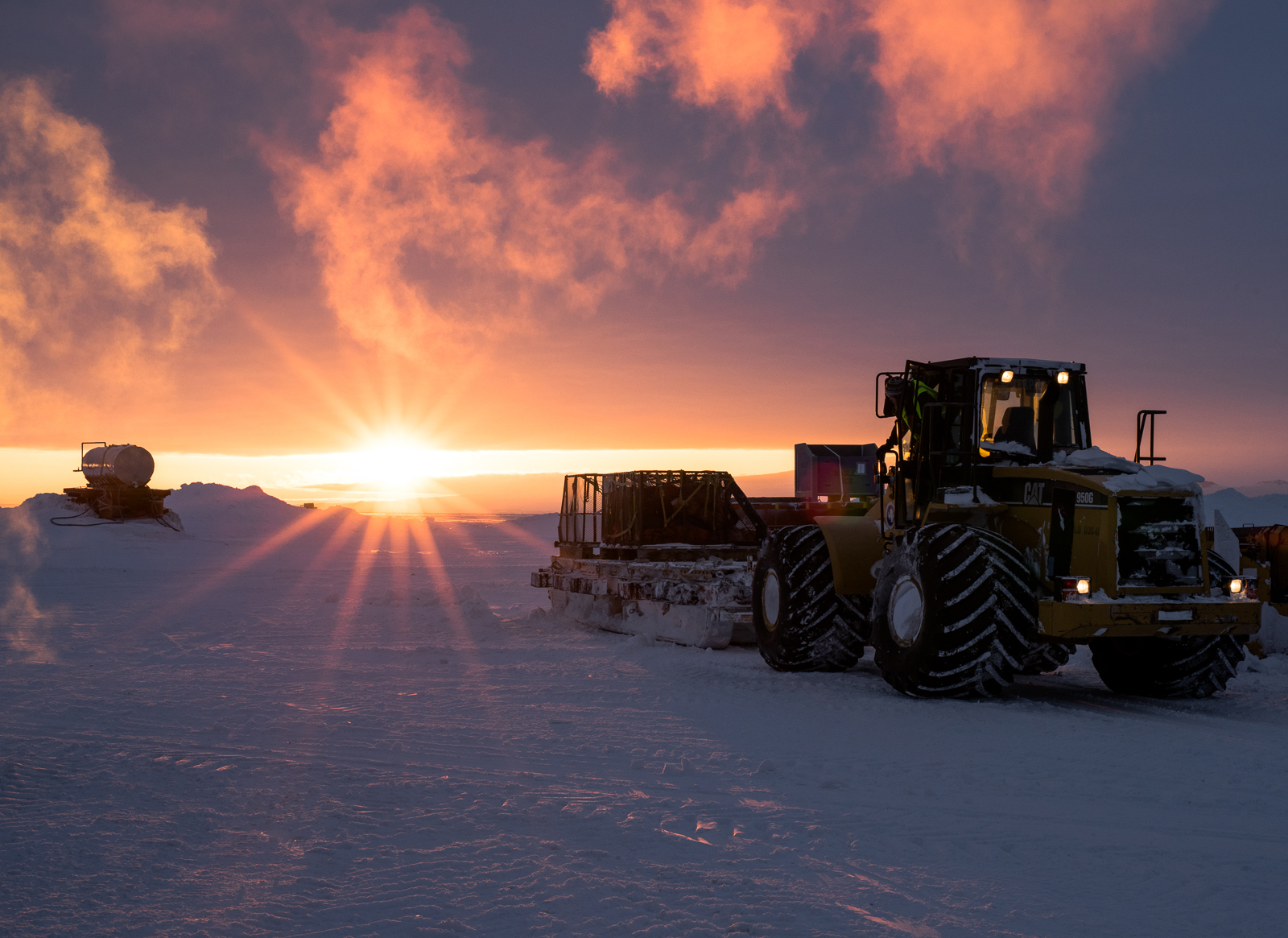 A sunrise with a tractor and sled.