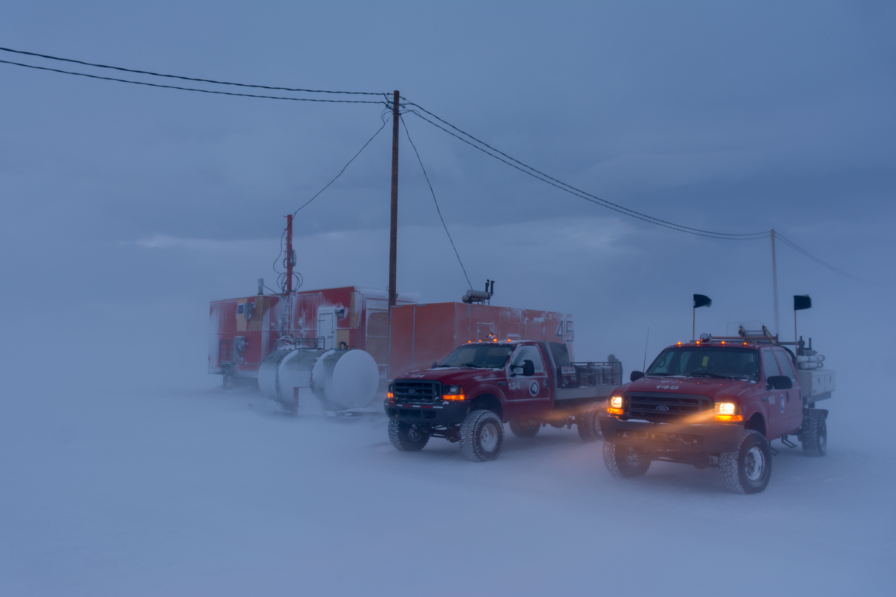 Two trucks sit in bad weather.