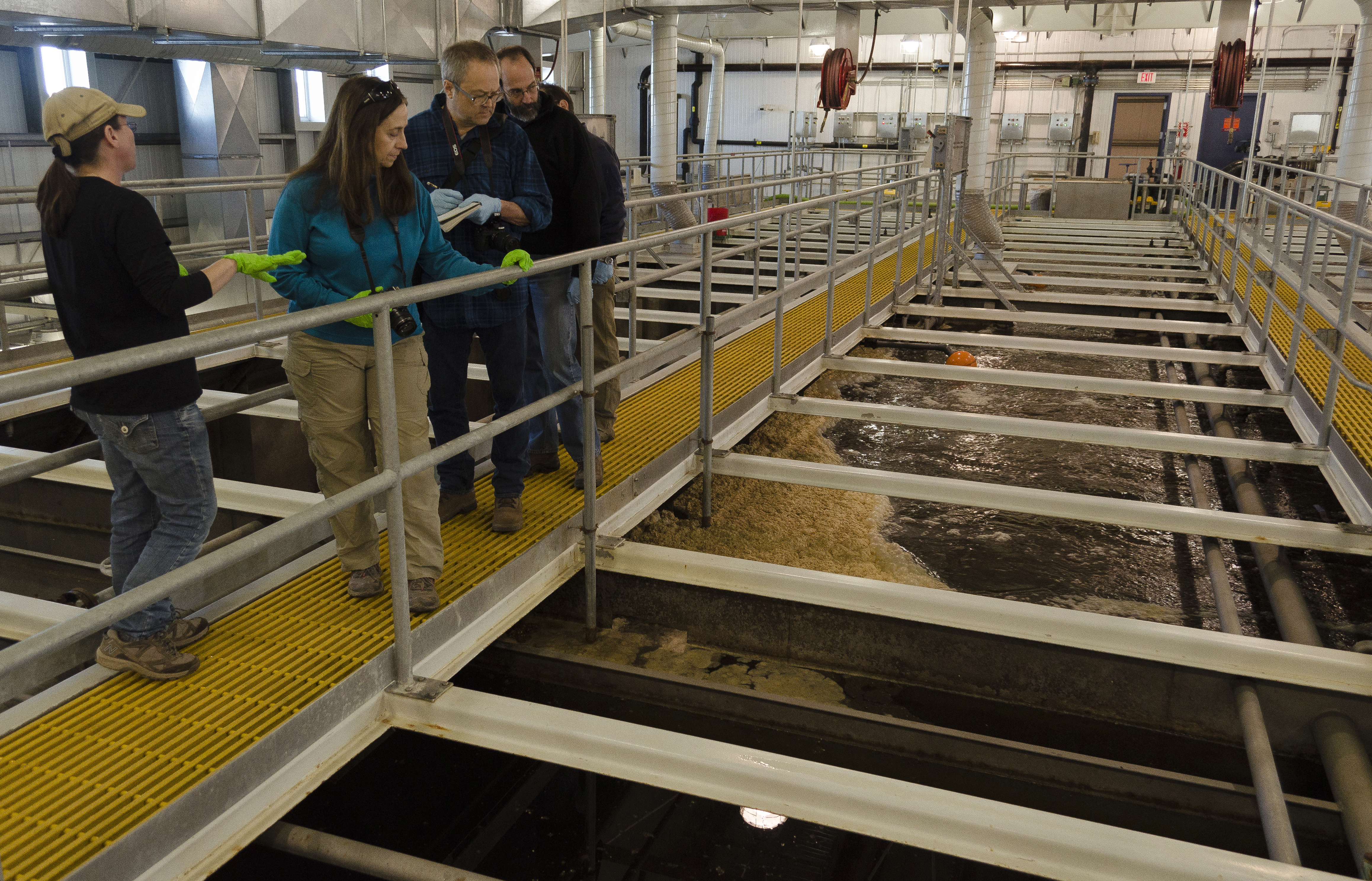 People stand on walkway near brown water.