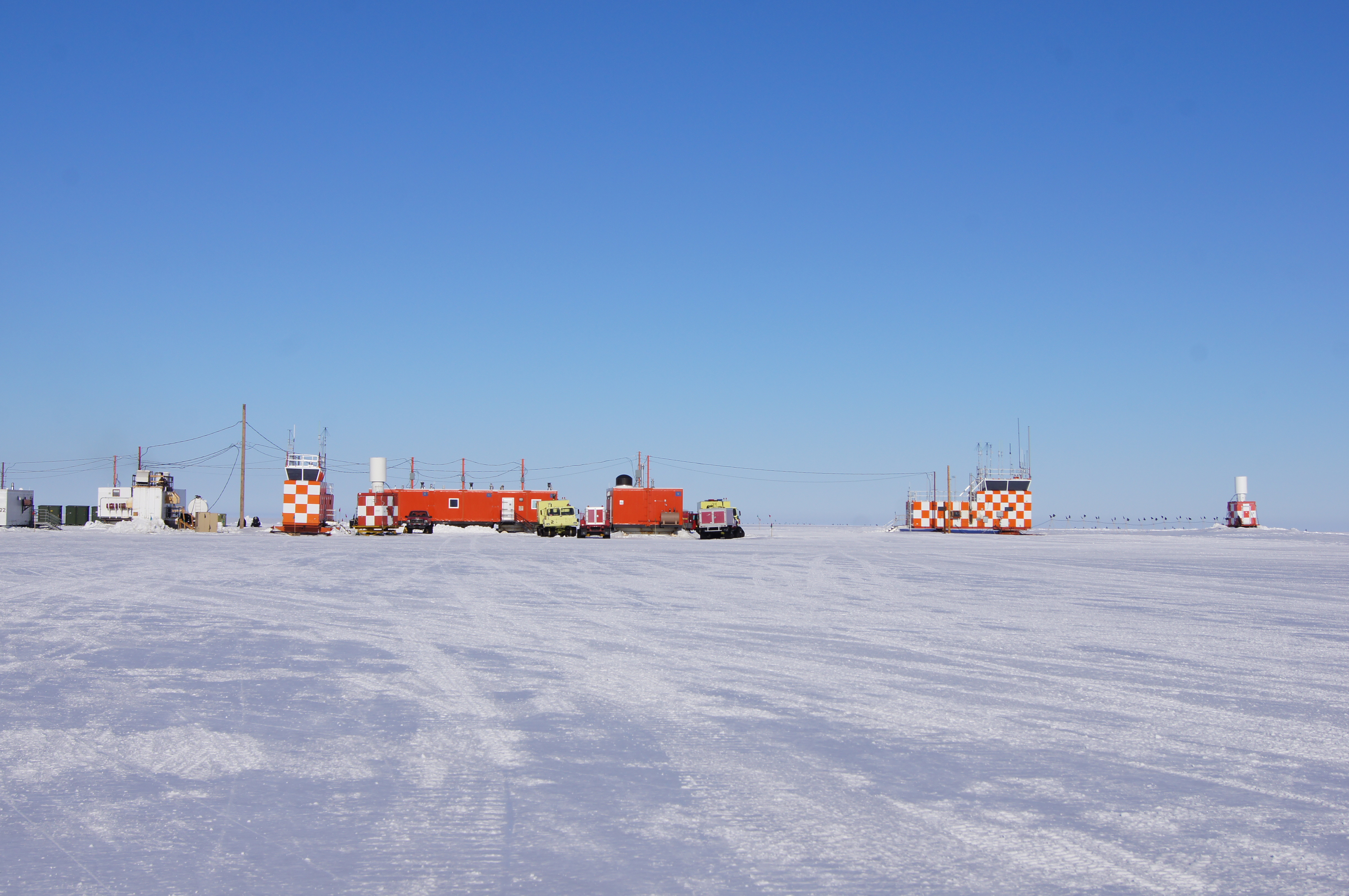 Several orange buildings sit on a plain of ice.